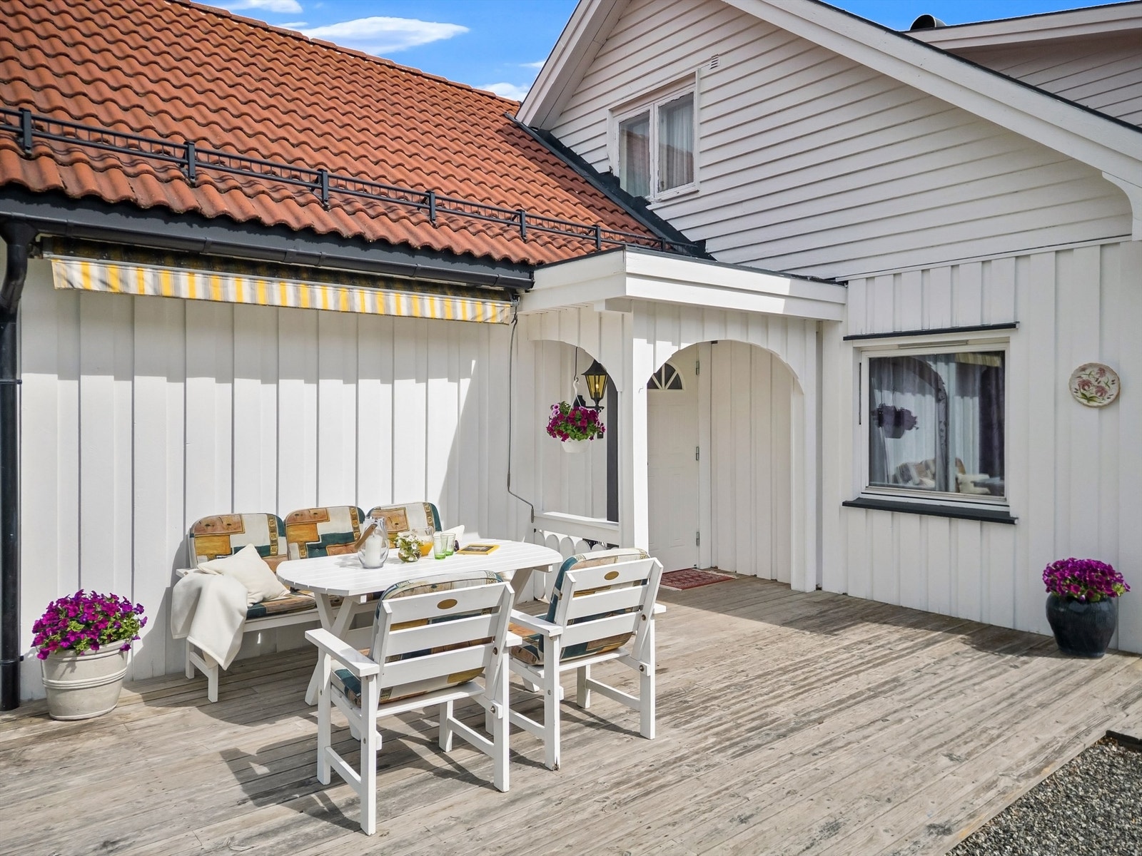 Koselig inngangsparti med fin terrasseplatting med markise og god plass til utemøbler Galleribilde