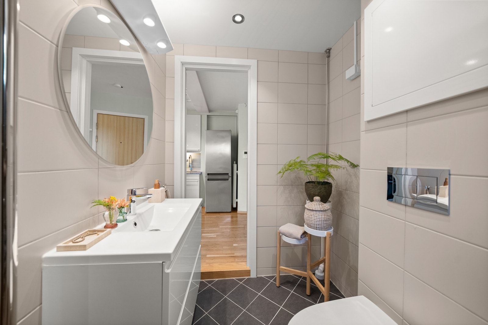 Badet har veggmontert toalett, opplegg for vaskemaskin, samt et dusjhjørne med innfellbar glassdør, håndgarnityr og regnfallsdusj. Galleribilde