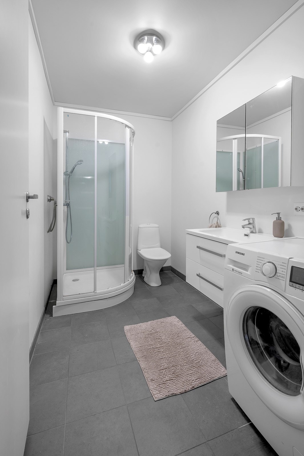 Badet har opplegg til vaskemaskin og duskabinett med toalett og servant. Galleribilde