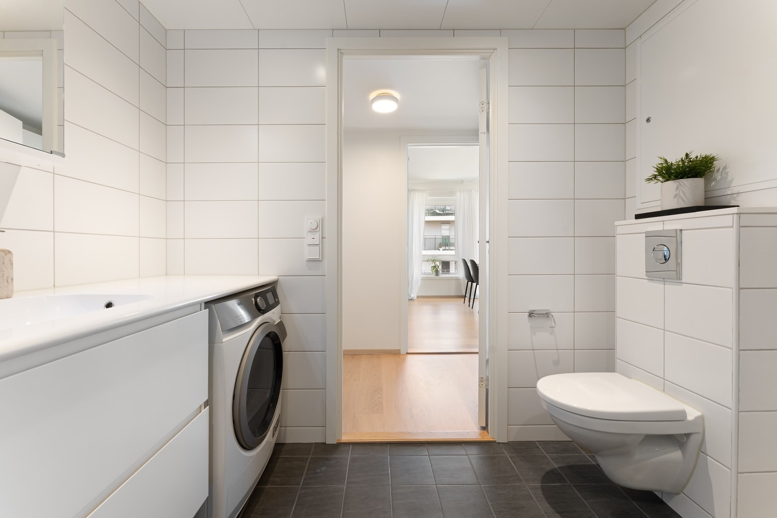 Badet er innredet med dusjhjørne med to svingbare glassdører, vegghengt toalett og en stilren baderomsinnredning med heldekkende servant. Galleribilde