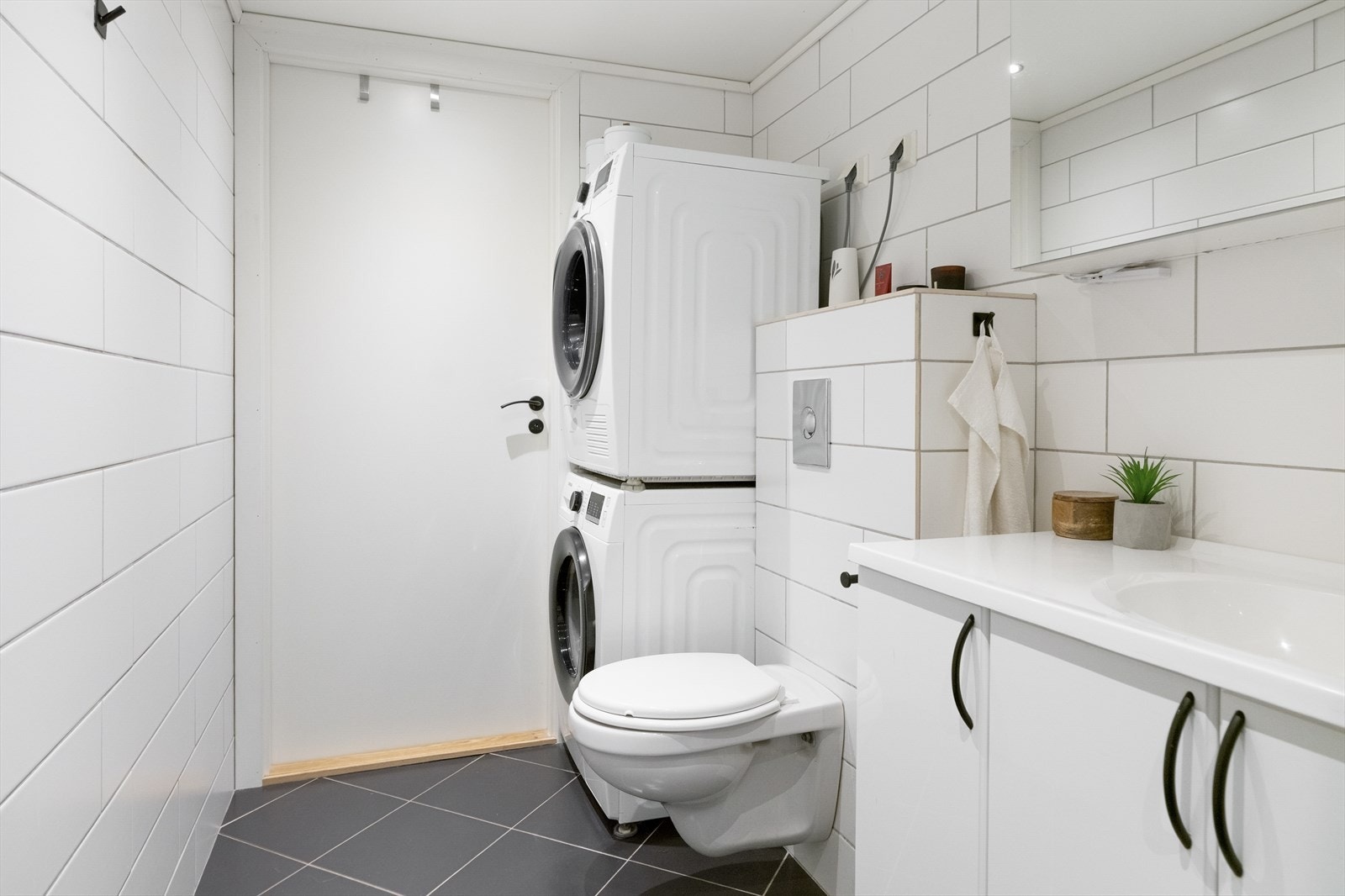Badet er innredet med servant med skuffeseksjon, samt vegghengt toalett og dusj. Badet har varmekabler i gulvet og opplegg for vaskemaskin og tørketrommel. Galleribilde