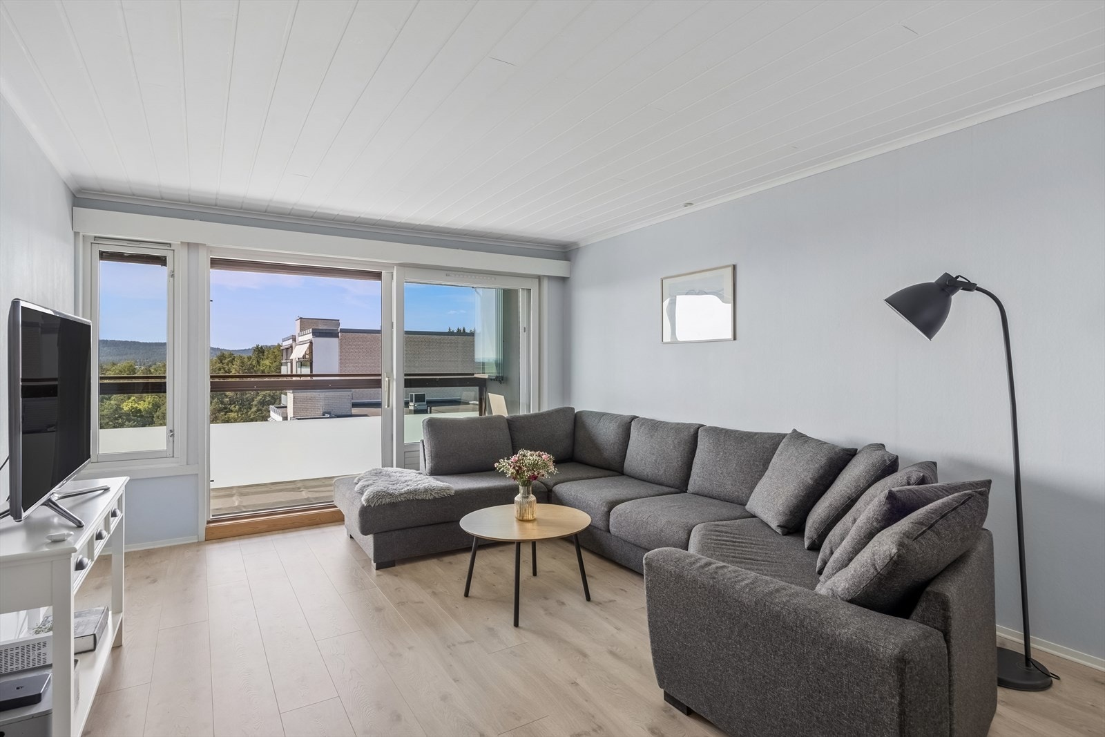 Lys og innbydende stue med store vindusflater og utgang til innglasset balkong. Galleribilde