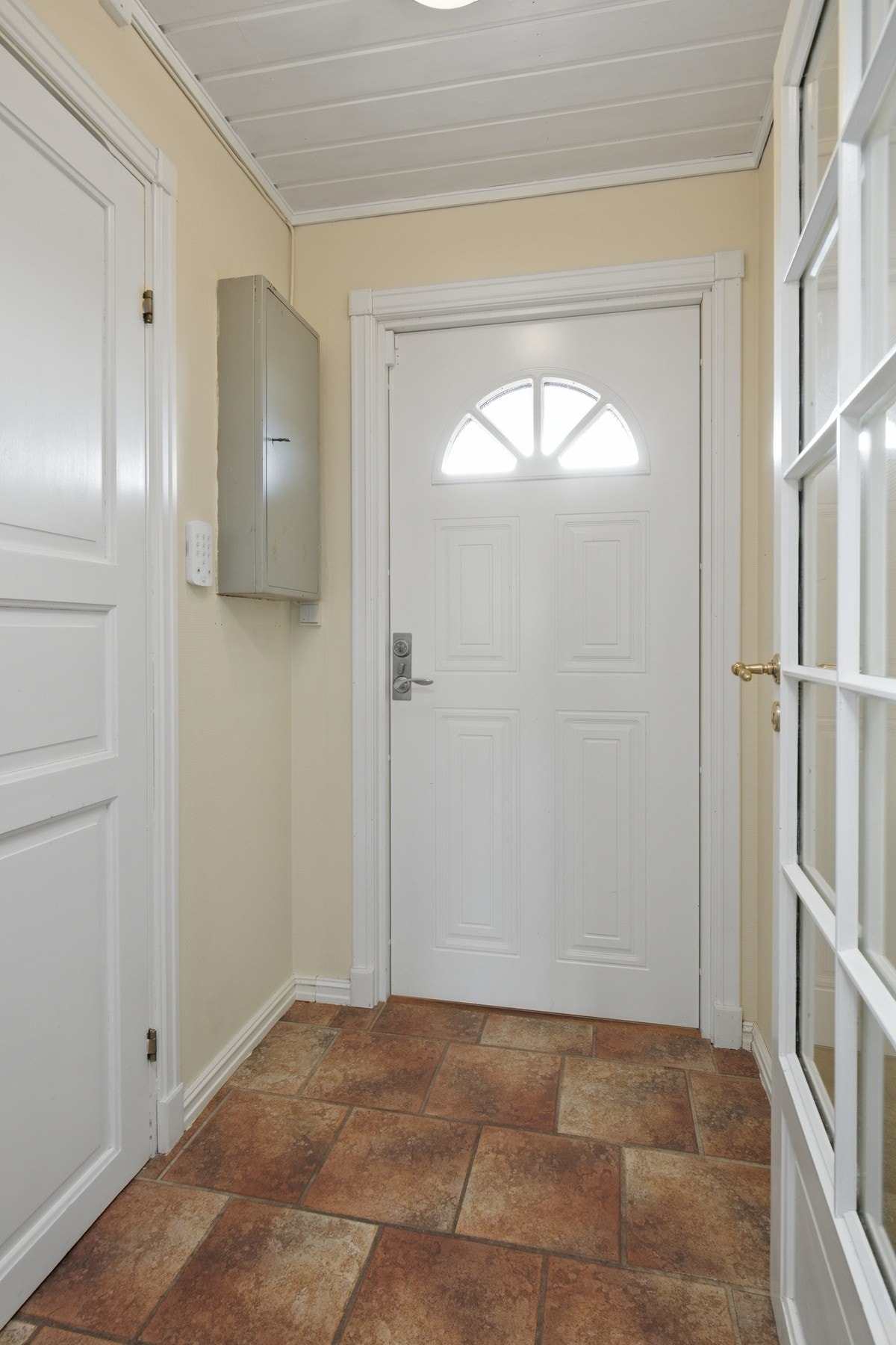 Vindfanget er lyst og innbydende med fliser på gulv med gulvvarme, lysmalte veggflater, hvitmalt og panelhimling Galleribilde