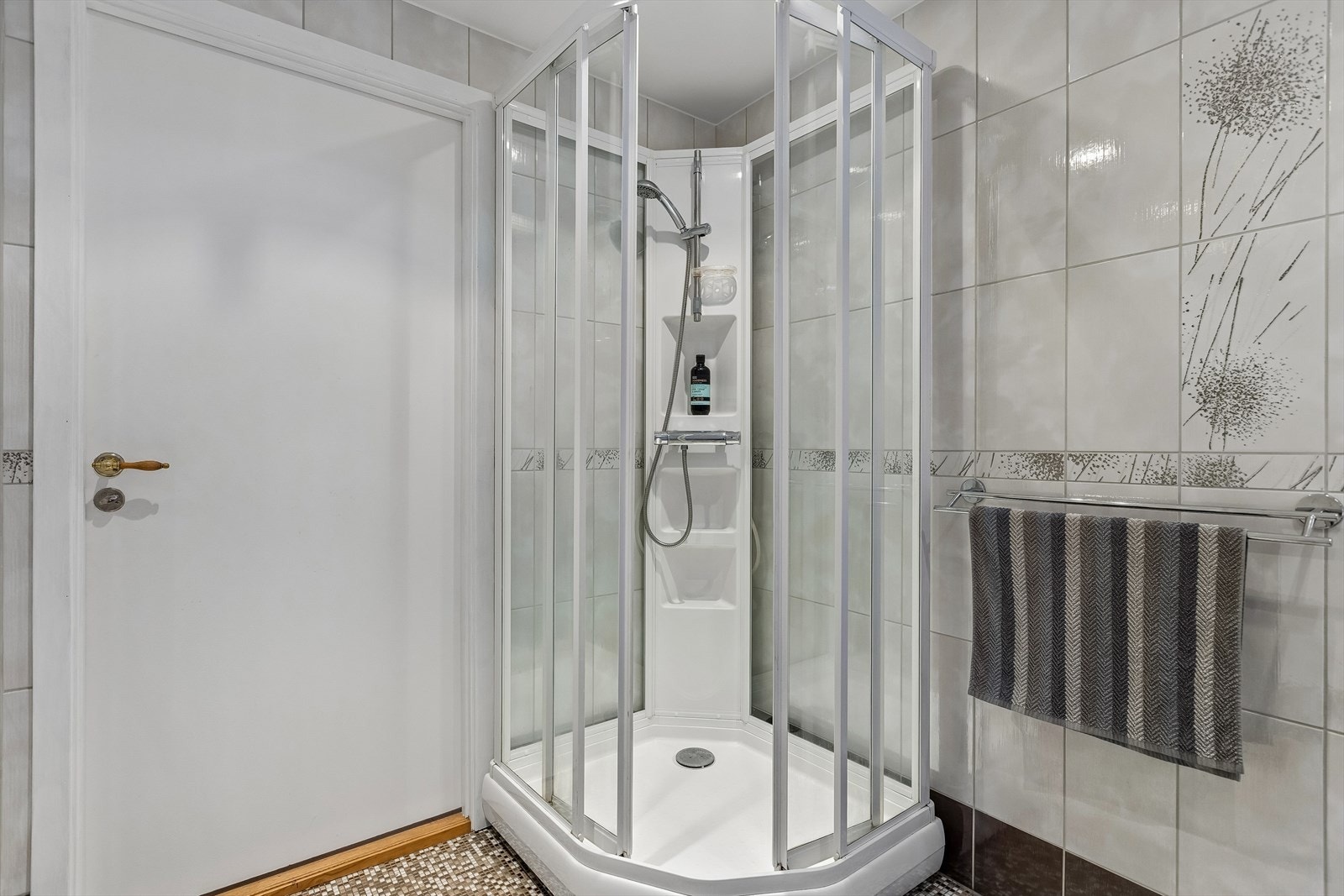 Dusjhjørne med dusjkabinett. Mosaikkfliser på gulvet gir badet et helhetlig preg. Galleribilde