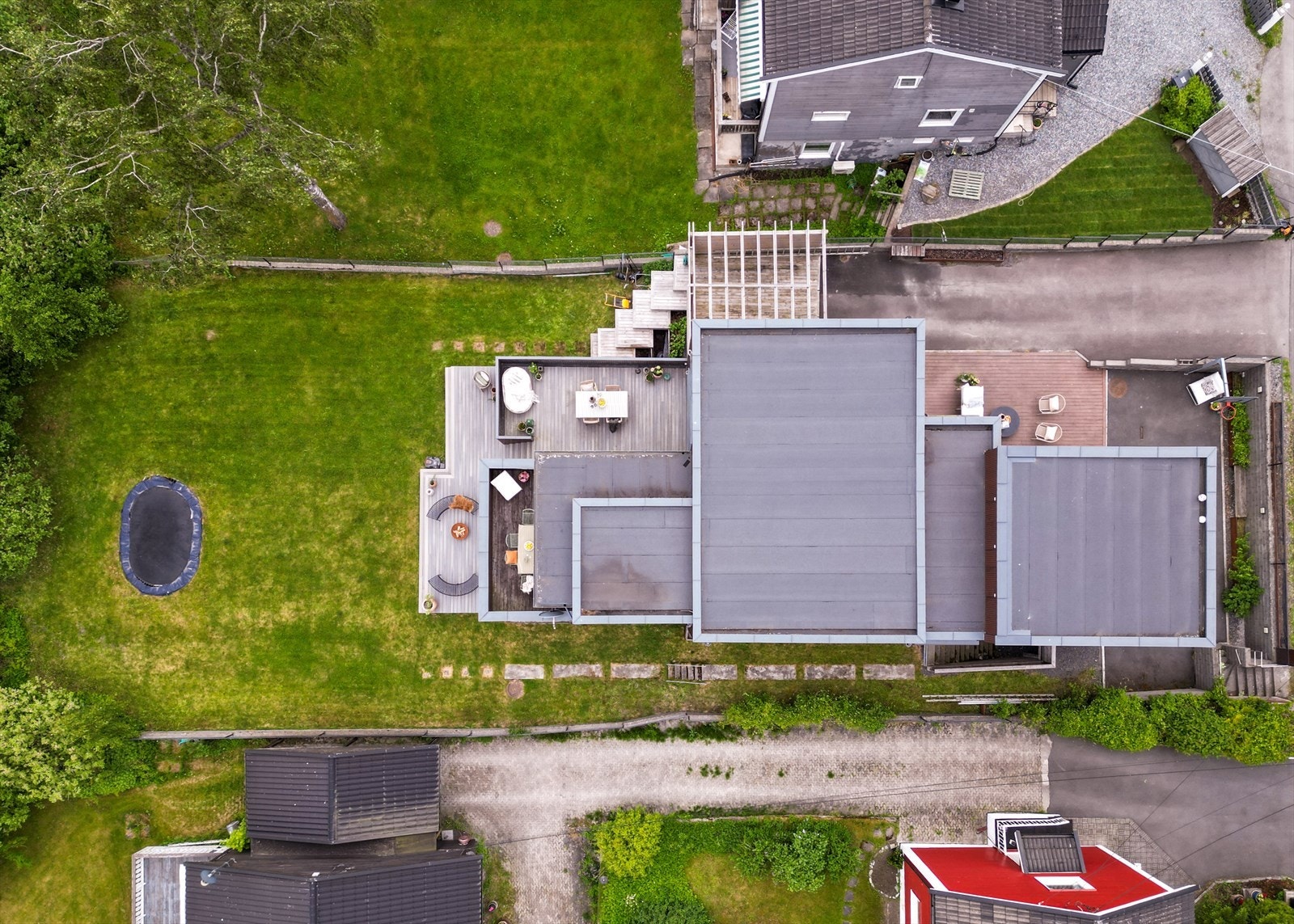 Huset sett ovenfra, med sine flotte uteområder, terrasser og mange bruksmuligheter. Gjerdet rundt tomten bidrar til en tydelig avgrensning mot naboeiendommene. Galleribilde