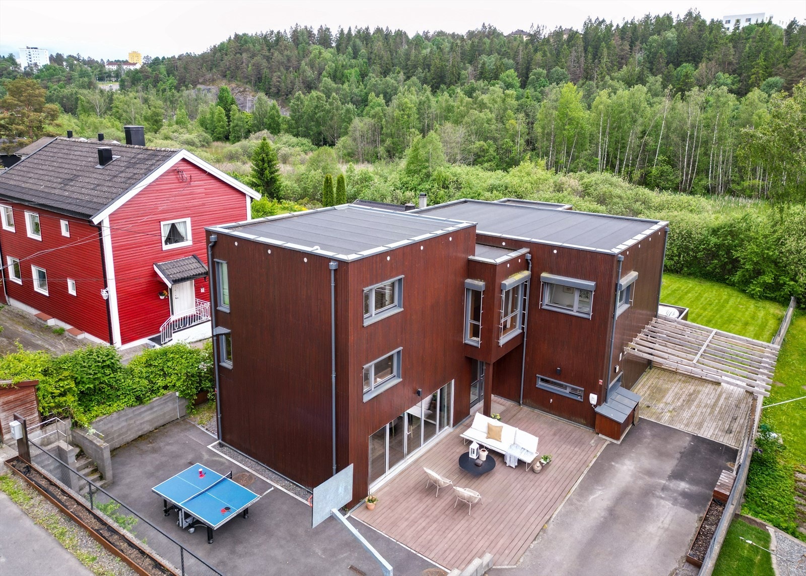 Dronebilde er retusjert. Strømledninger mellom mastene er fjernet for å gi mer oversiktlig inntrykk av eiedommen. Bak vegetasjonen i forkant av boligen ligger et grøntområde. Området er fredet, noe som bidrar til å bevare de naturskjønne omgivelsene. Galleribilde