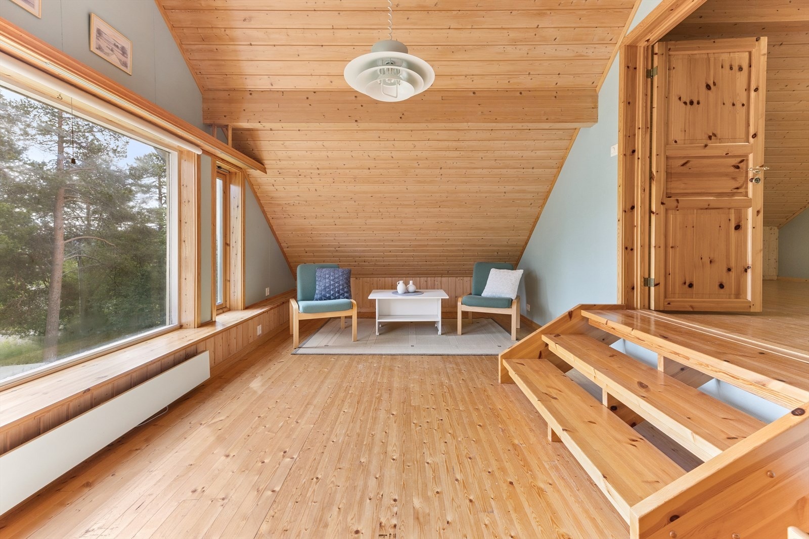 Loftsetasjen har en romslig stue med store vinduer og trepanel i himling. Galleribilde