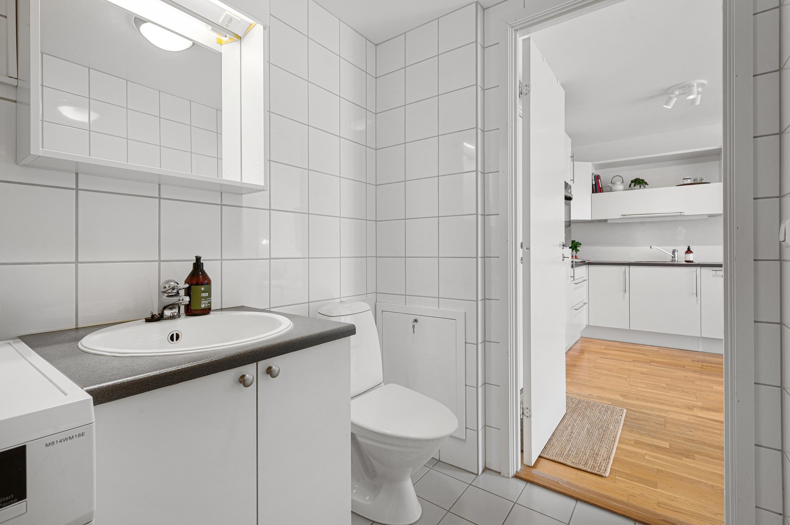 Baderommet består av dusjhjørne, gulvmontert WC, rørskap, kran og avløp for vaskemaskin, servant med underskap og speil. Galleribilde