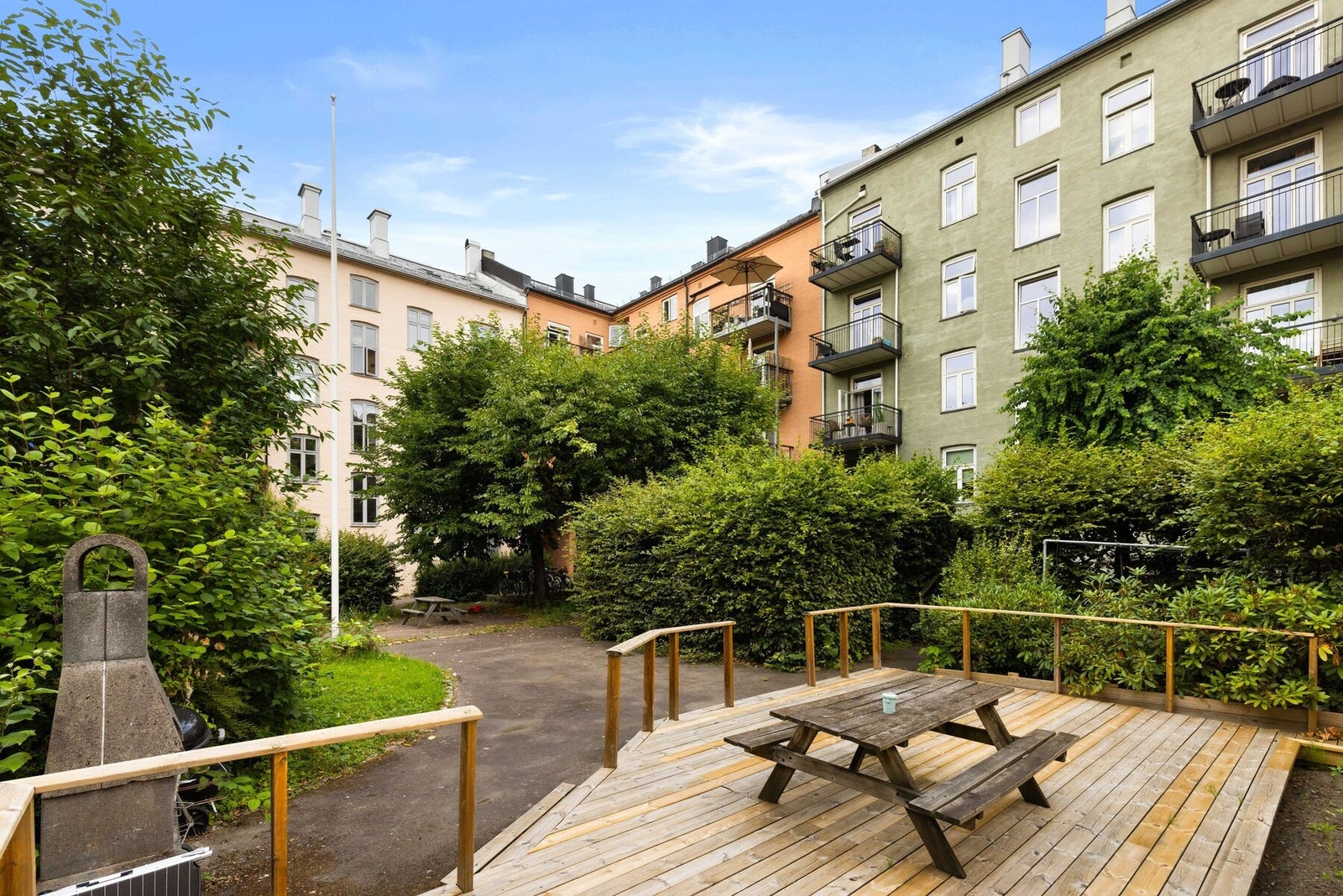 Felles bakgård opparbeidet med frodig beplantning, platting, sittegrupper og grill Galleribilde