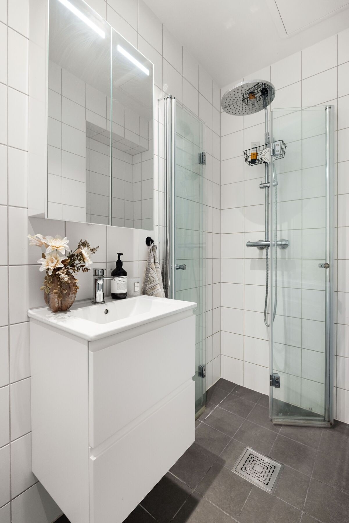 Badet har en moderne innredning bestående av servant med underskap, toalett, dusjhjørne med dusjvegger samt opplegg for vaskemaskin Galleribilde
