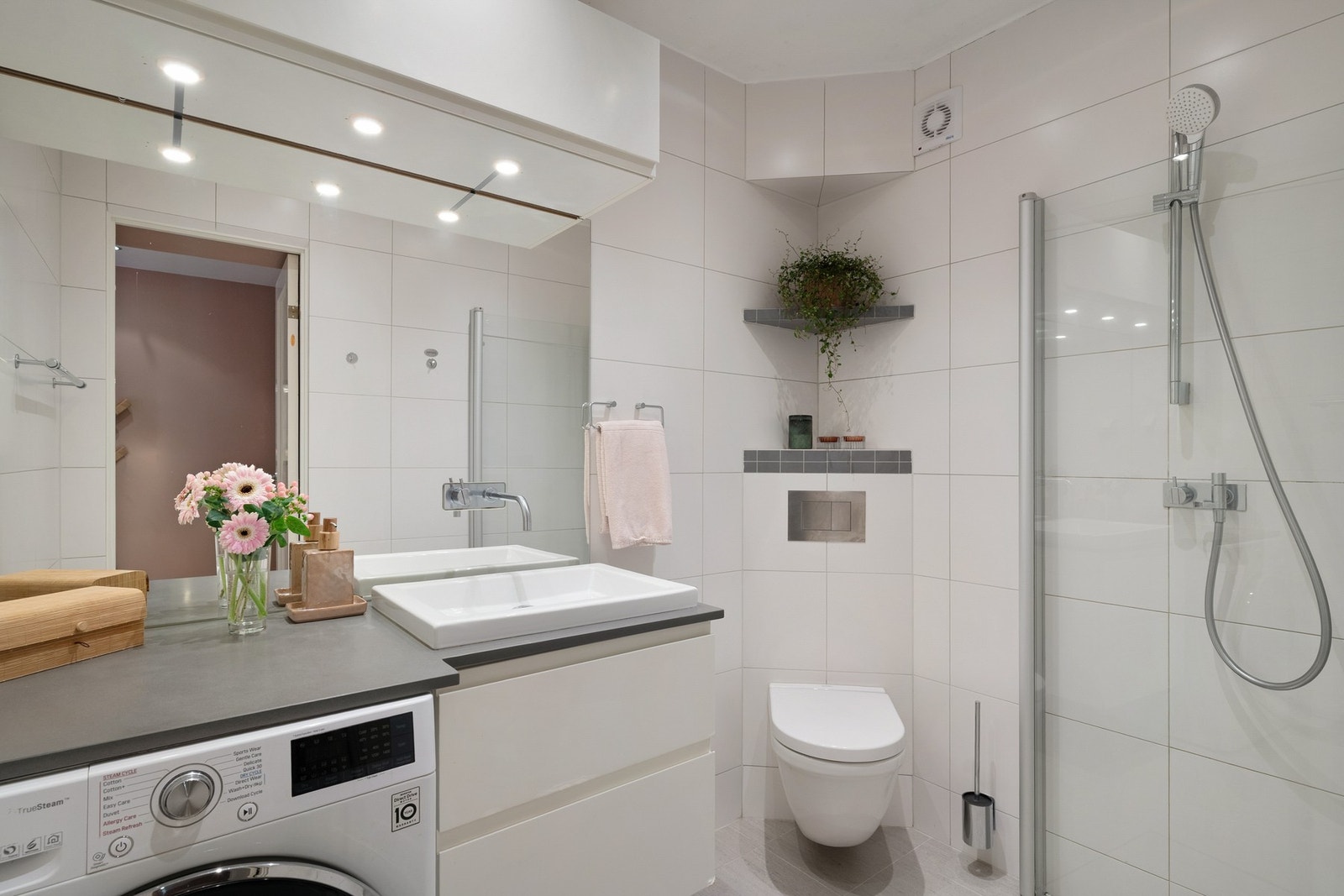 Badet er innredet med heldekkende servant på underskap, vegghengt toalett og dusjhjørne med innfellbare glassdører - en praktisk og gjennomført løsning. Galleribilde