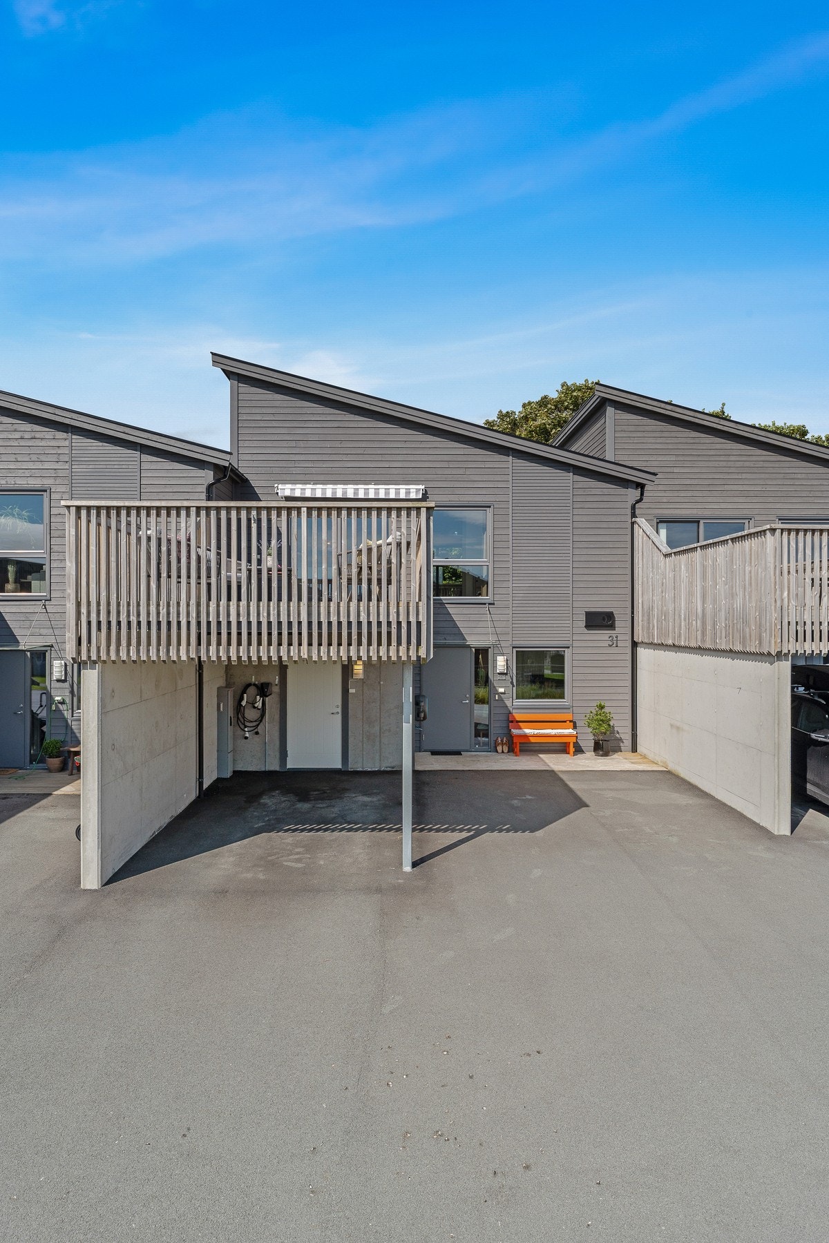 Fasade. Parkering i carport. Asfaltert gårdsplass. Galleribilde