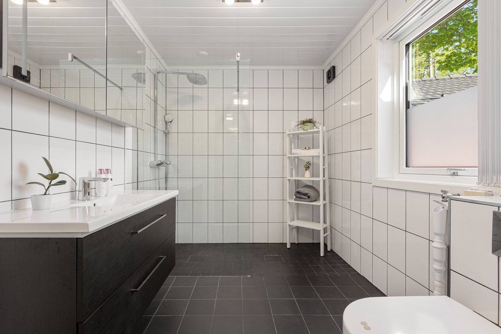 Badet i 1. etasje er romslig og har et moderne uttrykk med flislagte gulv og vegger, samt behagelige varmekabler i gulvet. Innredningen består av et servantskap med nedfelt servant og veggskap med speildører. Galleribilde