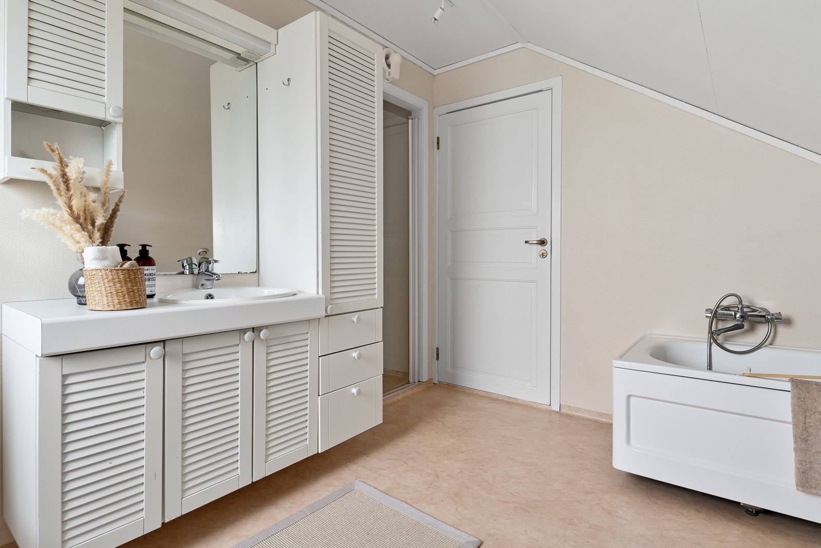 Badet er utstyrt med dusjnisje, badekar, toalett og servant i baderomsinnredning med god oppbevaringsplass. Galleribilde