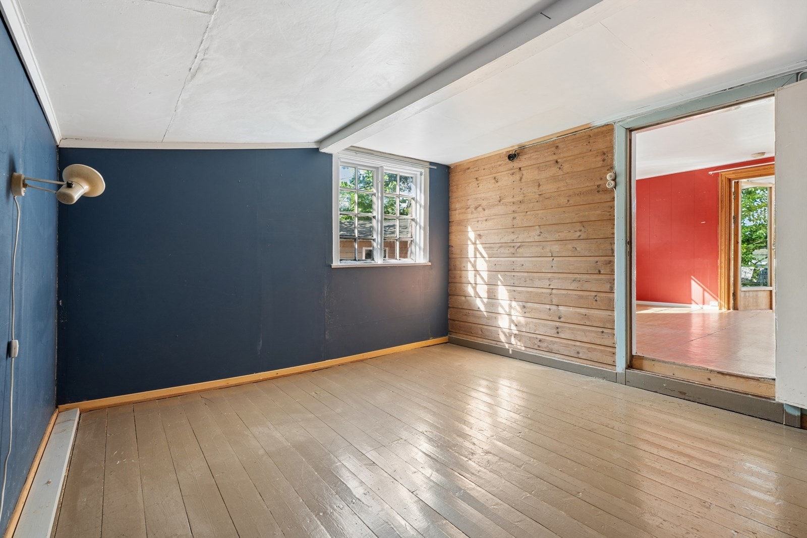 Det ene soverommet har en karakteristisk vegg med trepanel og malt tregulv. Galleribilde
