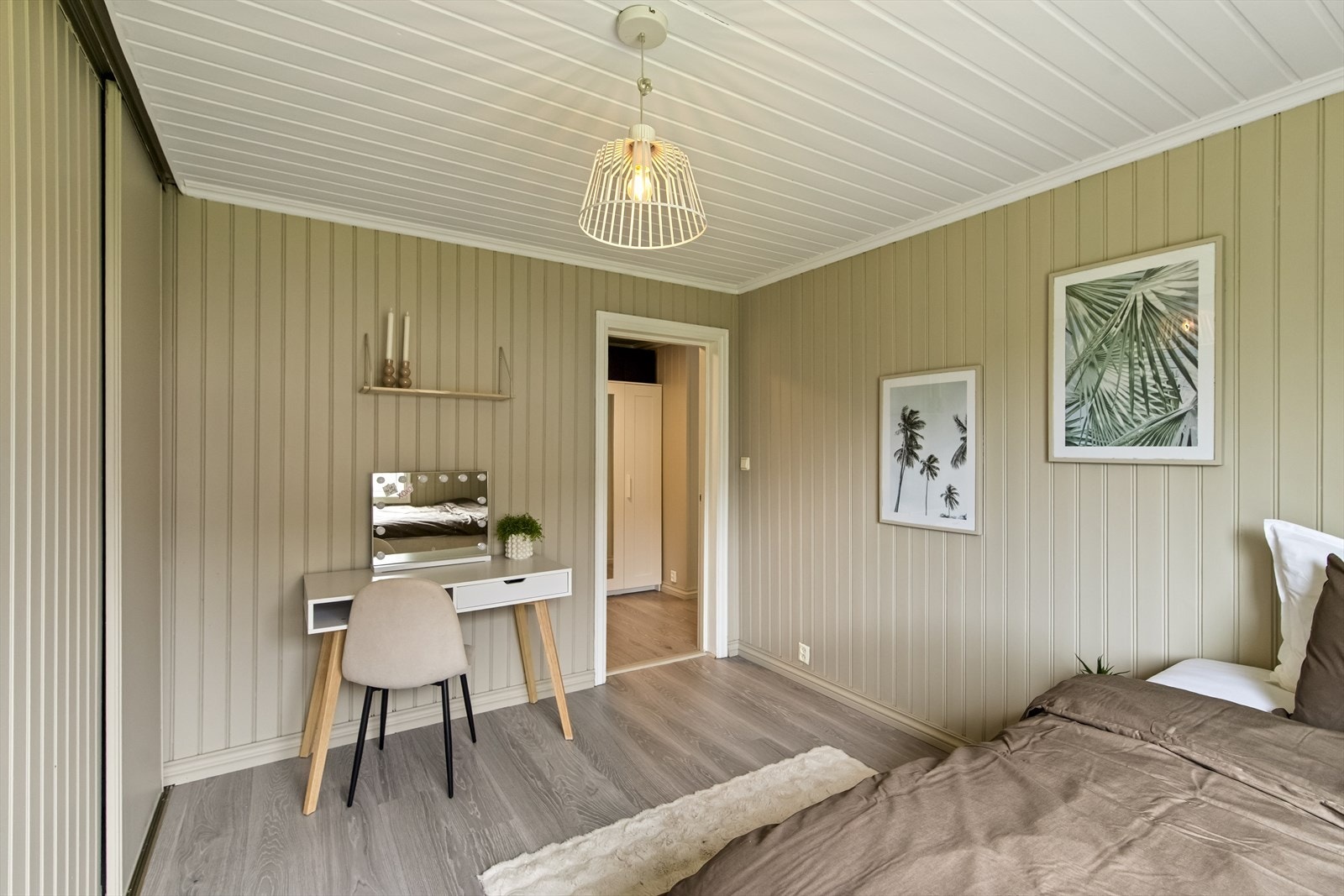 Integrert skyvedørsgarderobe gir utmerkede oppbevaringsmuligheter. Veggene er kledd i samme flotte panel i en rolig fargetone, og et stort vindu gir rikelig med lys. Galleribilde