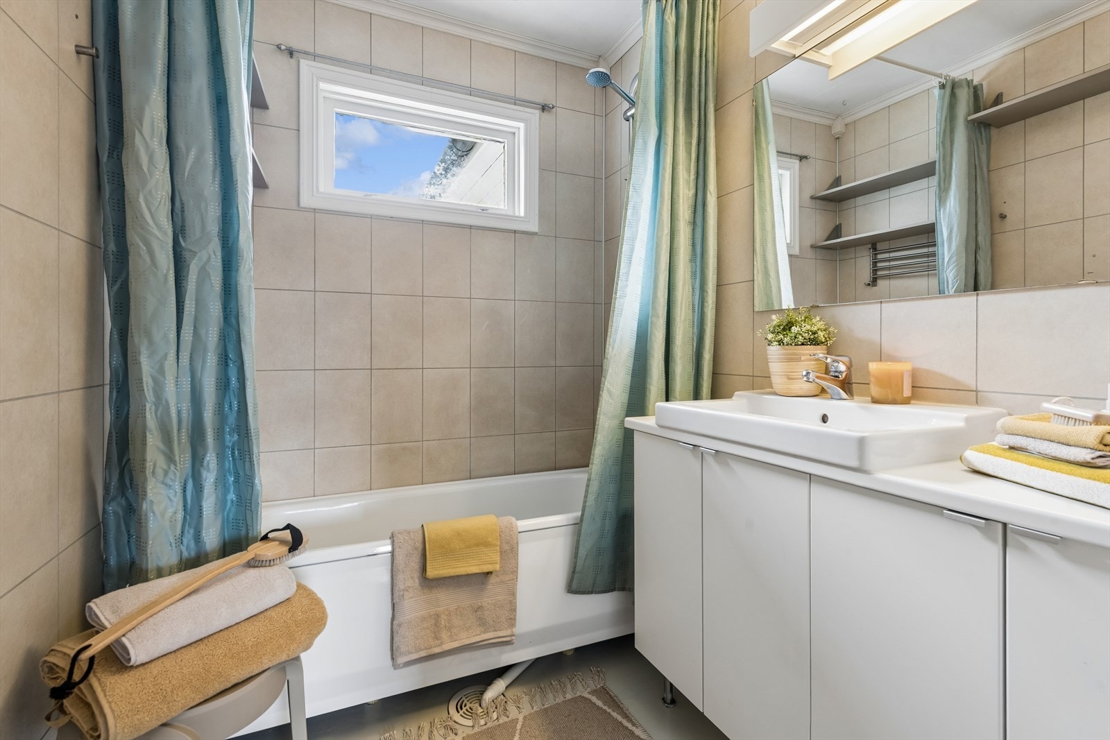 Badet har vinylbelegg på gulv, baderomsplater på veggene og badekar. Galleribilde