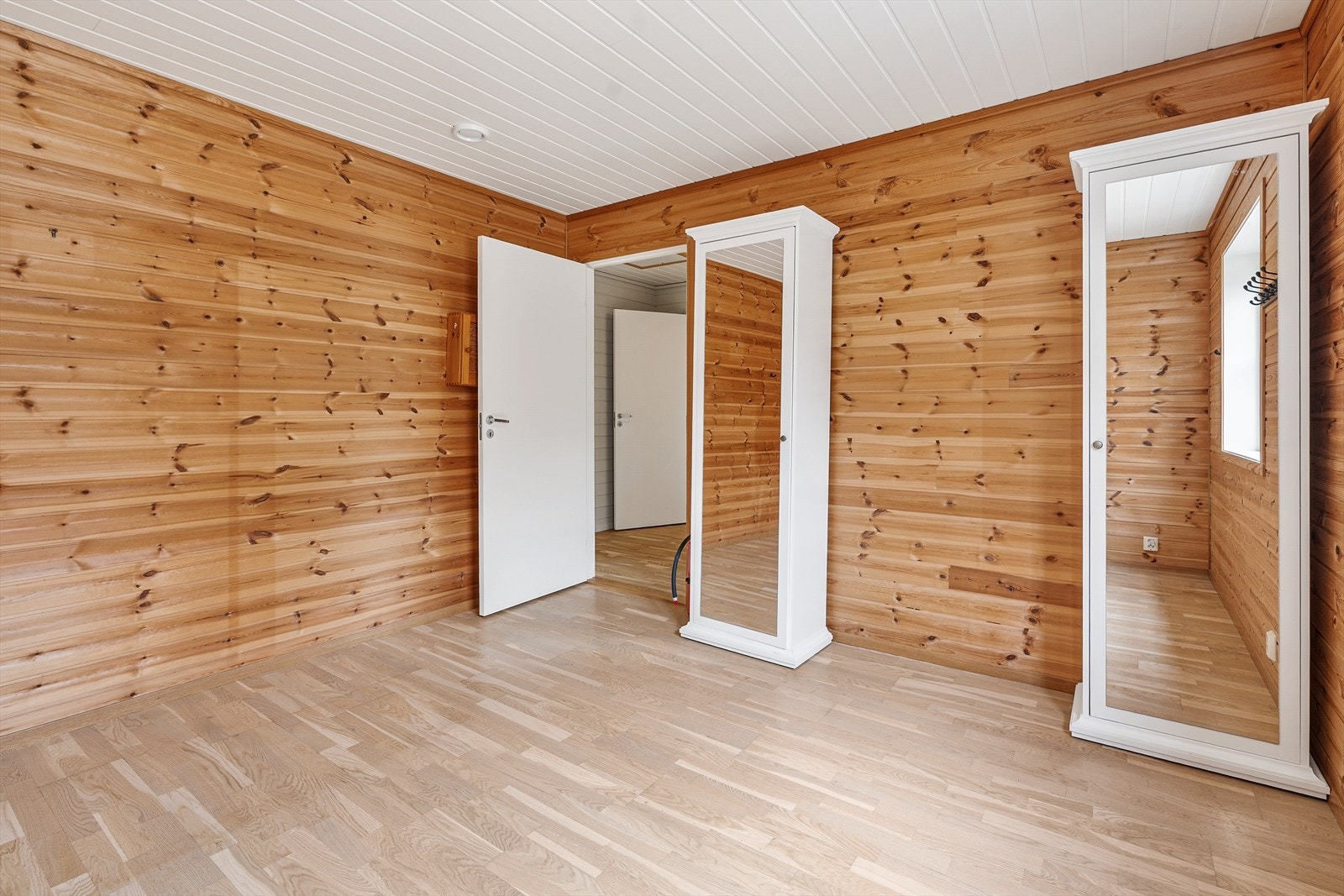 Romslig soverom med parkett på gulv og vegger i trepanel. Galleribilde