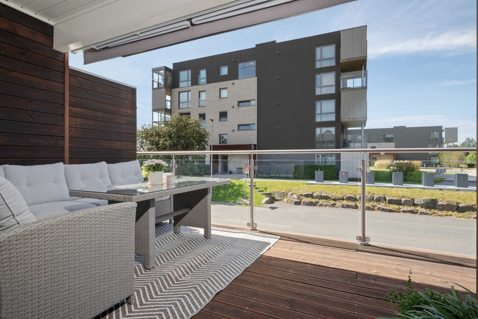 Terrassen har dekke av oljede terrassebord, levegger på siden og rekkverk av glass. Galleribilde