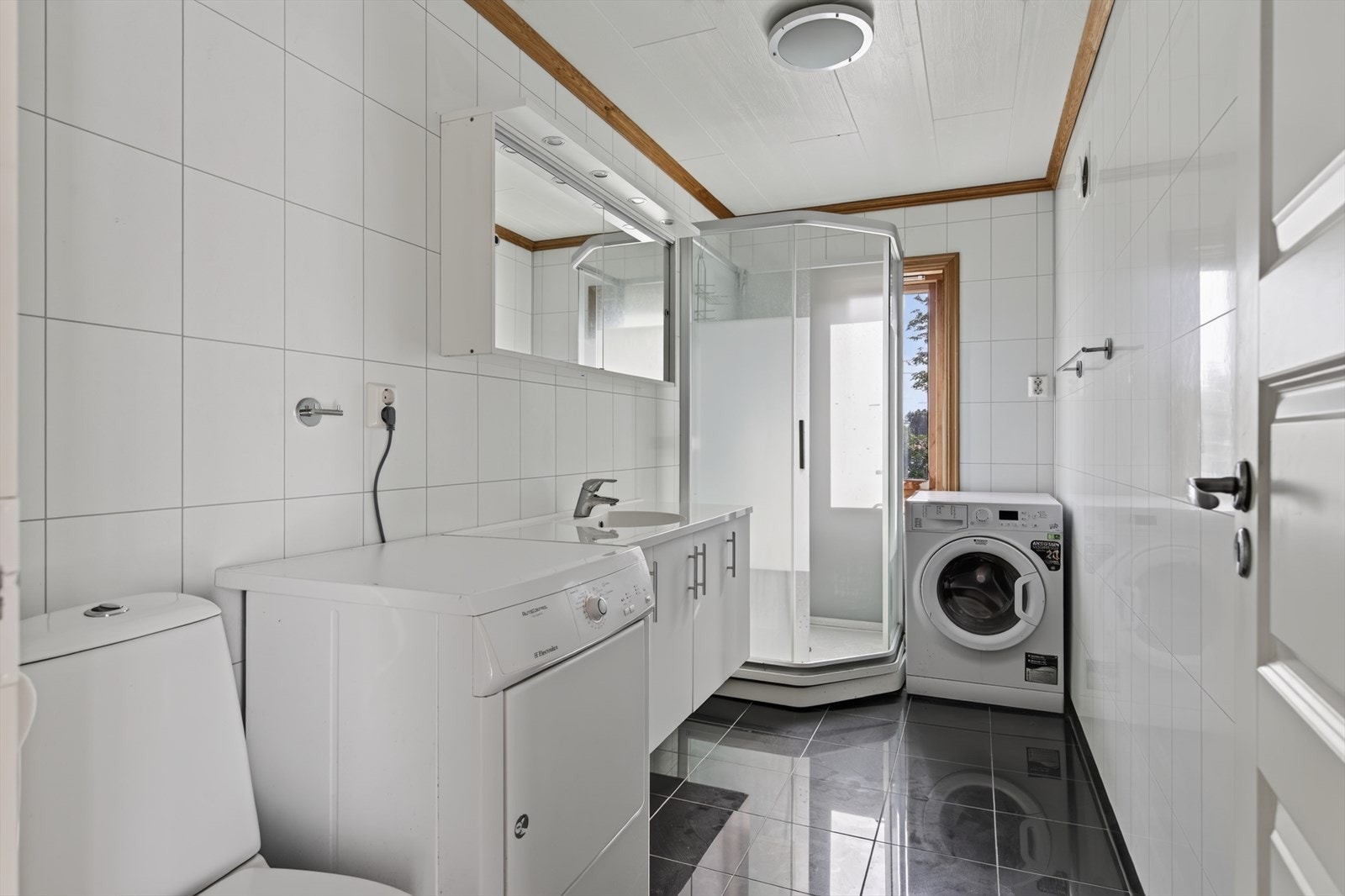 Badet har flislagt gulv med gulvvarme og opplegg for vaskemaskin. Galleribilde