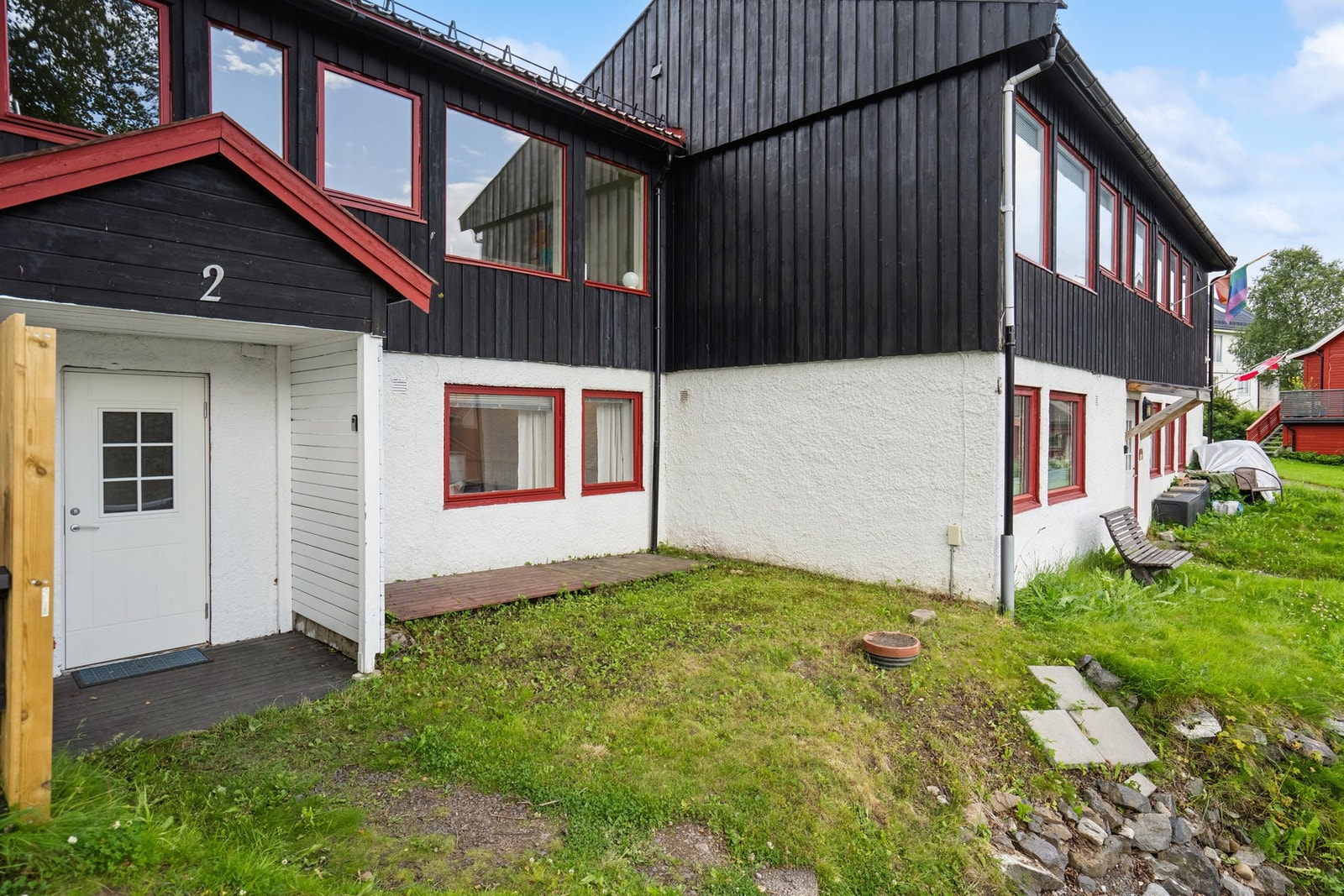 Bygningen ligger på en felles tomt som er opparbeidet med plen. Galleribilde