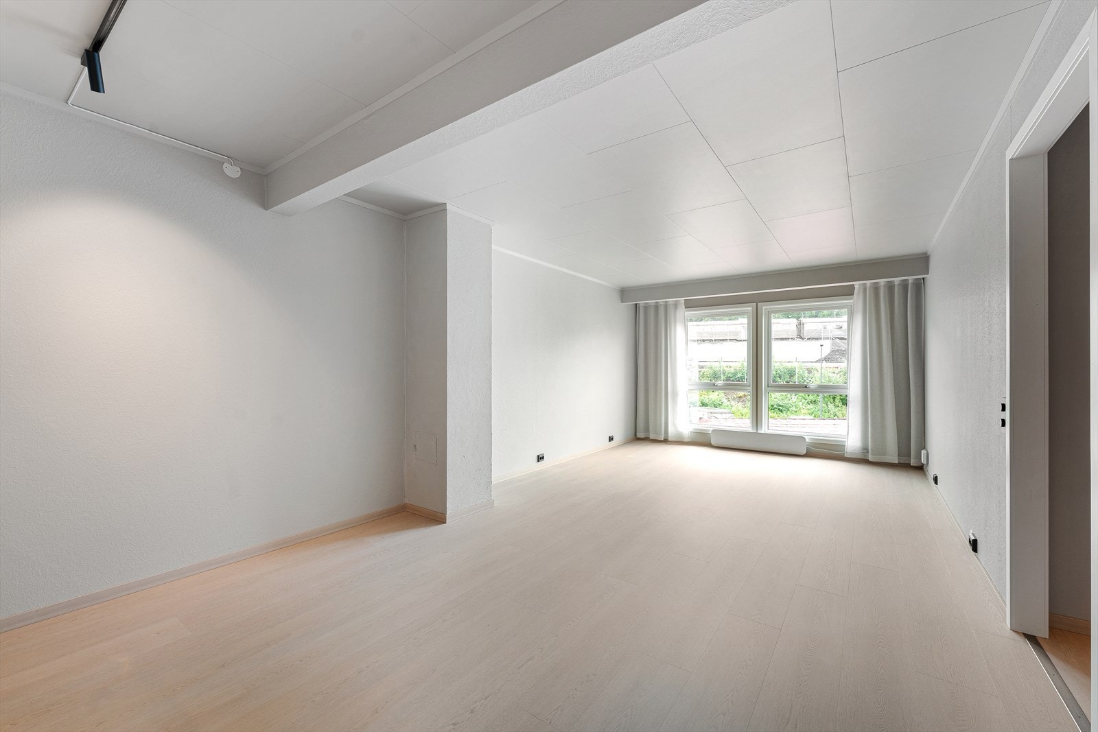 Lys og innbydende stue med store vindusflater som slipper inn rikelig med naturlig lys og skaper en luftig atmosfære. Rommet har nytt gulv fra 2026, som gir et moderne og helhetlig uttrykk. Galleribilde