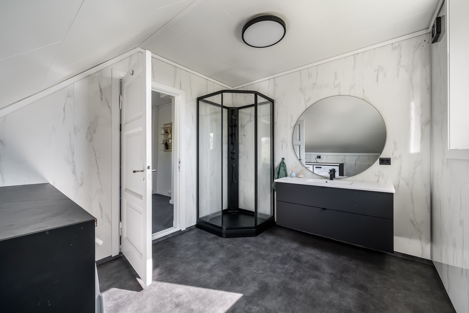 Romslig bad i overetasjen med moderne servantinnredning, dusjkabinett og praktisk vaskesone med plass til både vaskemaskin og tørketrommel. En funksjonell løsning som kombinerer bad og vaskerom på en praktisk måte. Galleribilde