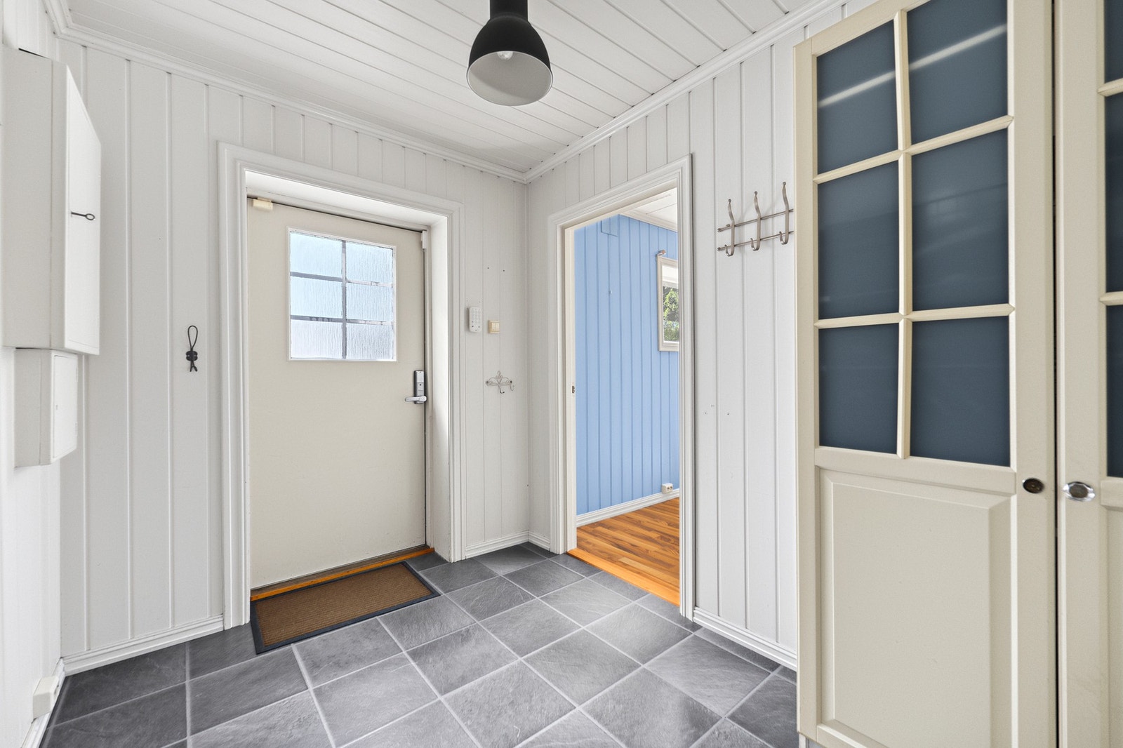 Eneboligen har en fin entré med hvit panel på veggene og grått flislaminat på gulvet. Galleribilde