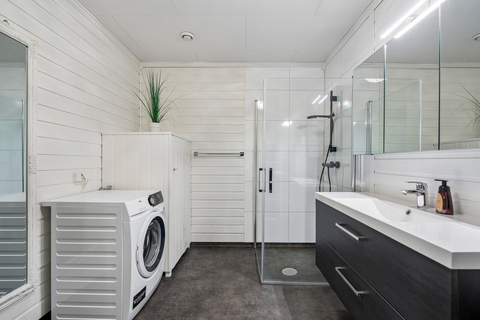Badet er praktisk innredet med dusj, servantinnredning, gulvvarme og opplegg for vaskemaskin. Galleribilde