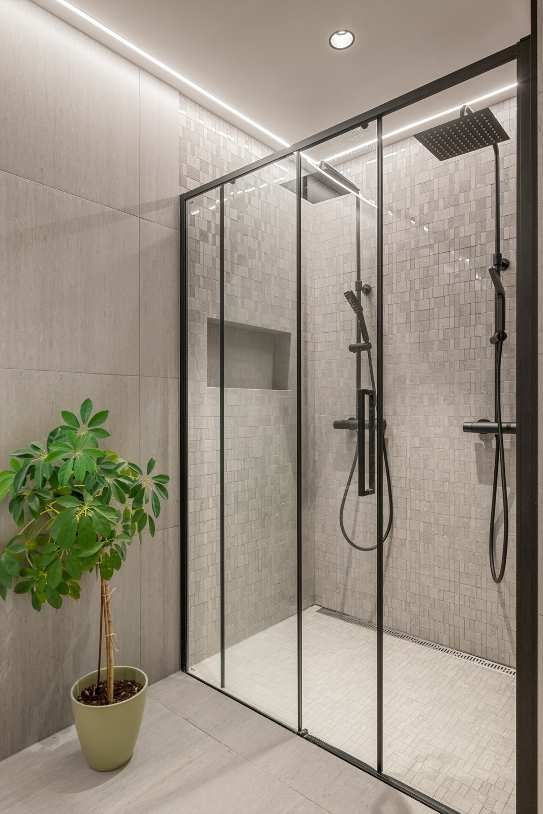 På badet nede er det også et stilig dusjhjørne med slukrenne, mosaikkfliser og dobbel regnfallsdusj. Galleribilde