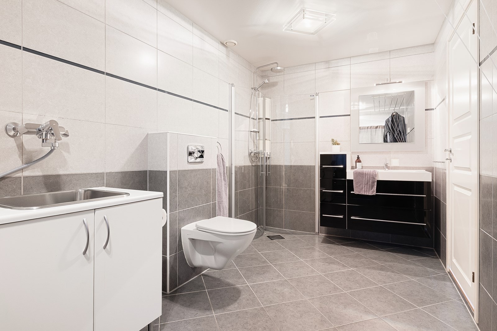 Badet er utstyrt med dusjhjørne, vegghengt toalett og opplegg for vaskemaskin. Galleribilde