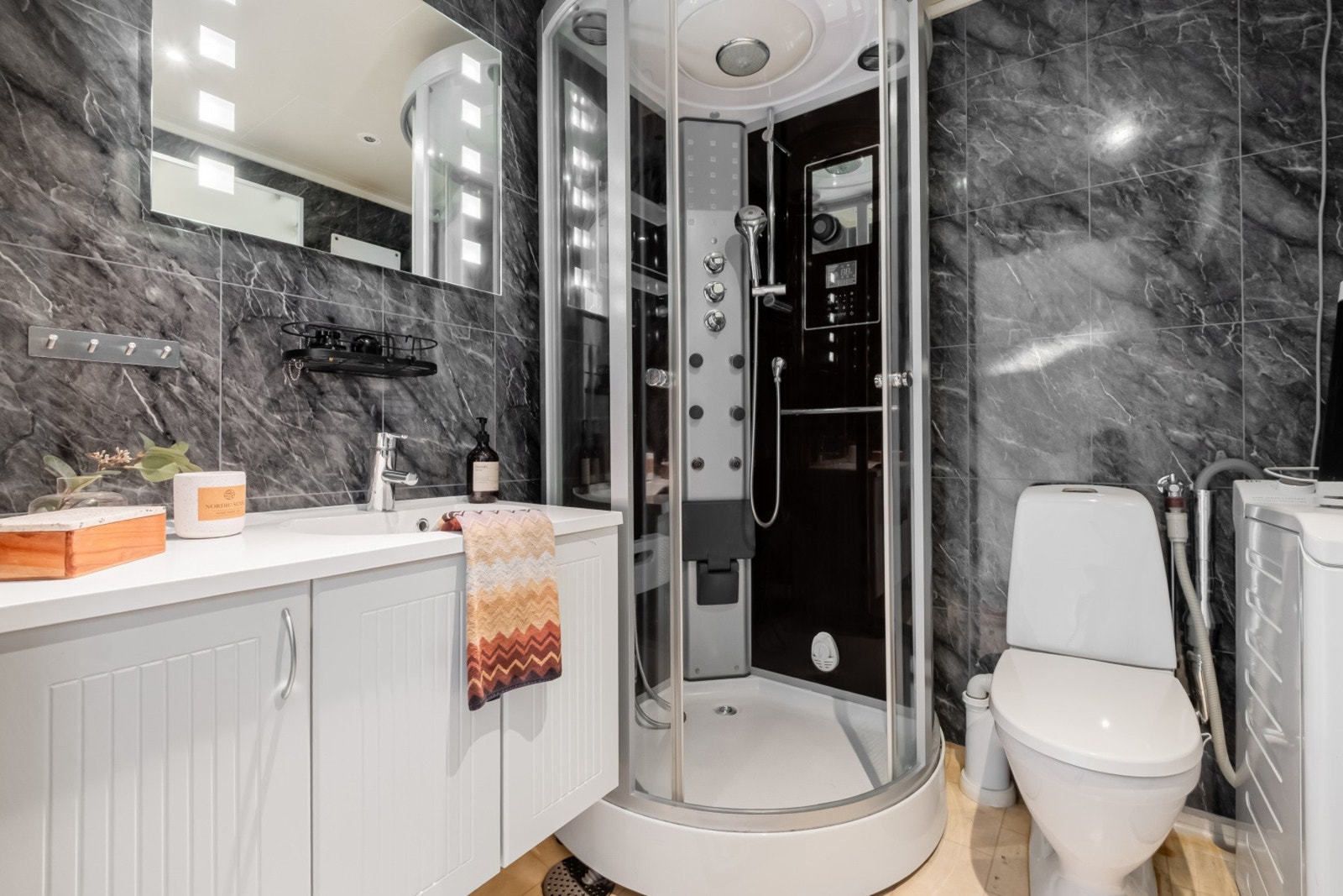 Badet har baderomsplater på veggene og er utstyrt med dusjkabinett. Galleribilde