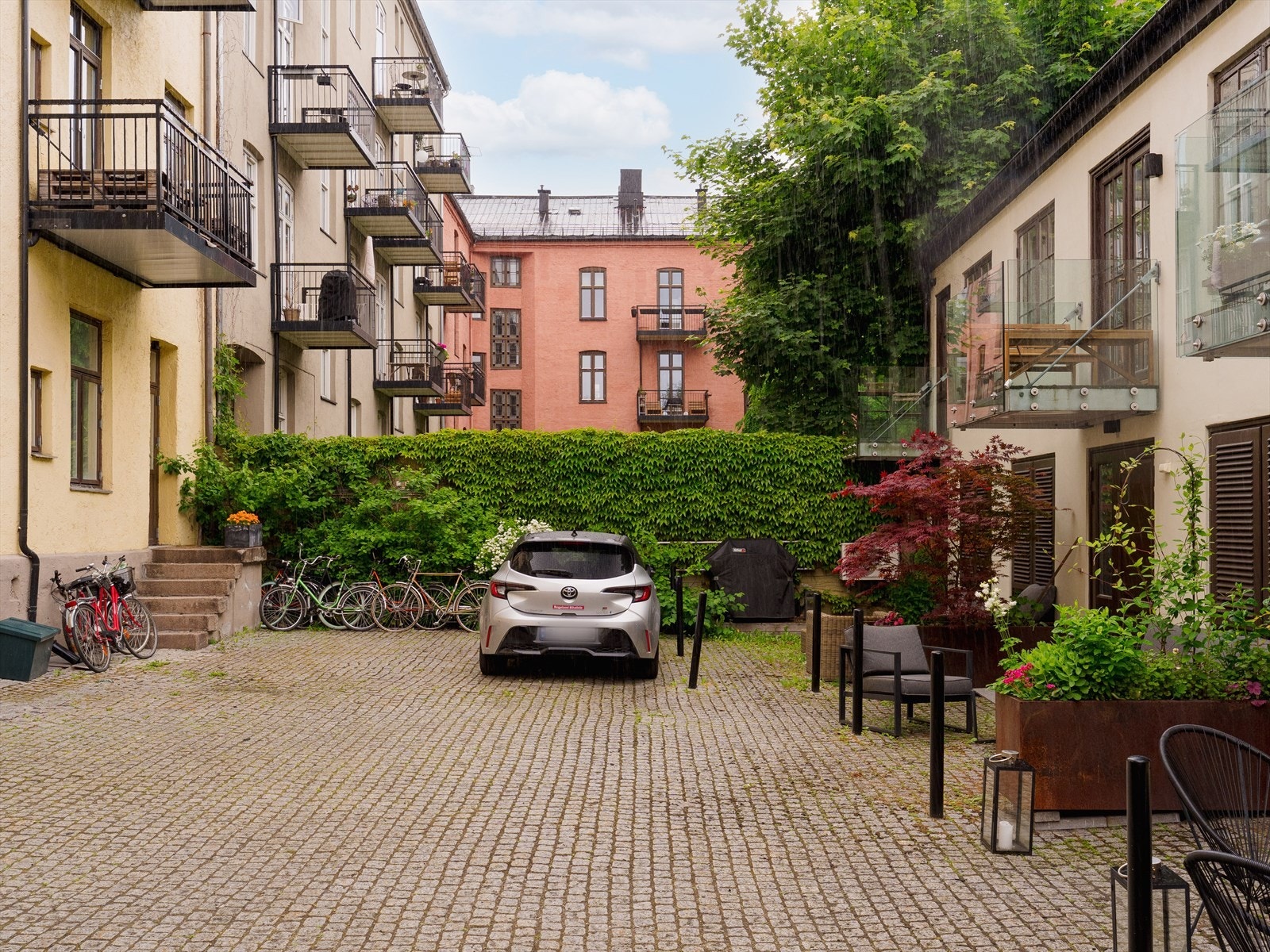 Bakgården er pent opparbeidet med brostein, beplantning og sykkelstativ. Galleribilde
