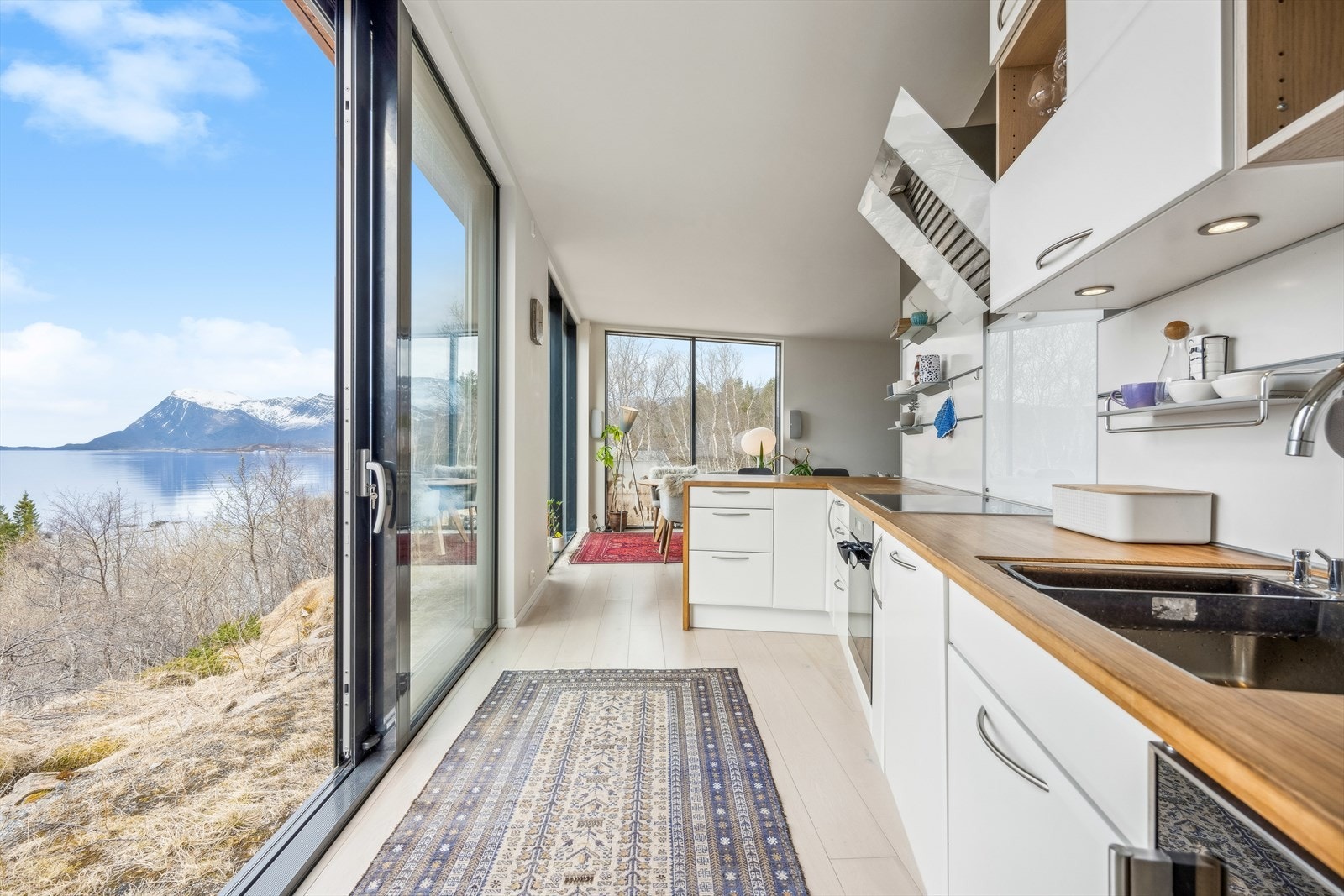 Stilrent kjøkken med Kitshenboard og glassplate over benk. Det er kjøkkenventilator med avtrekk ut. Galleribilde