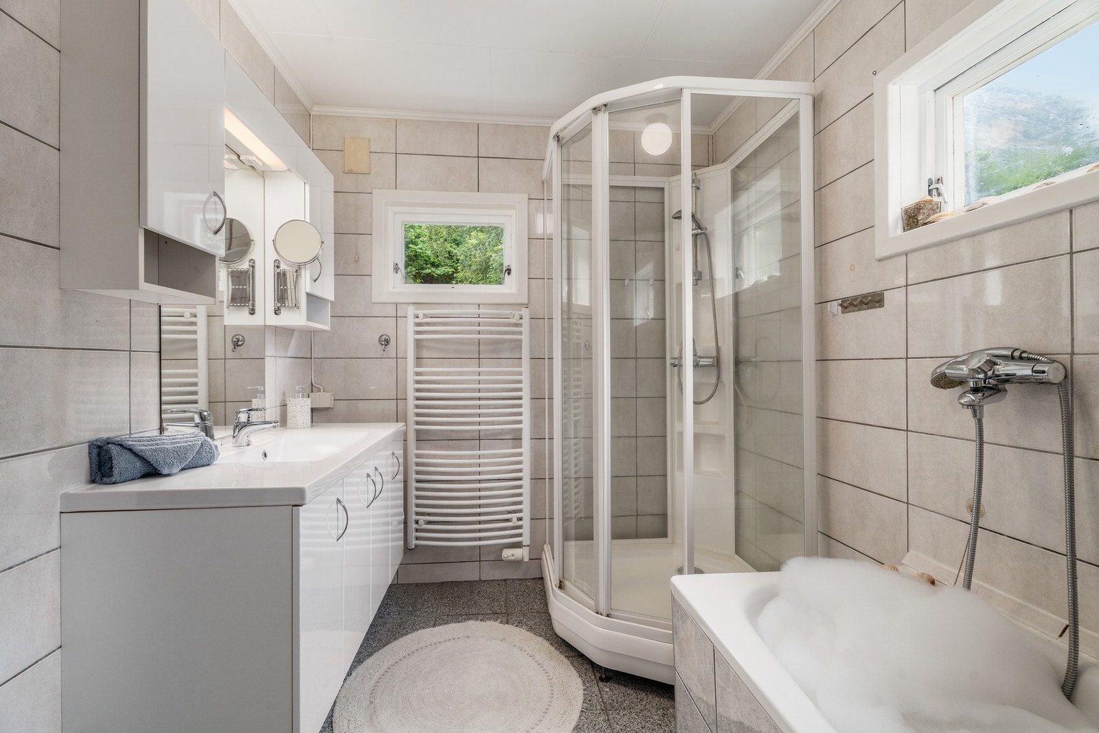 Flislagt bad med både dusjkabinett og badekar. Legg merke til innholdsrik servantinnredning. Badet har standard fra 2013. Galleribilde