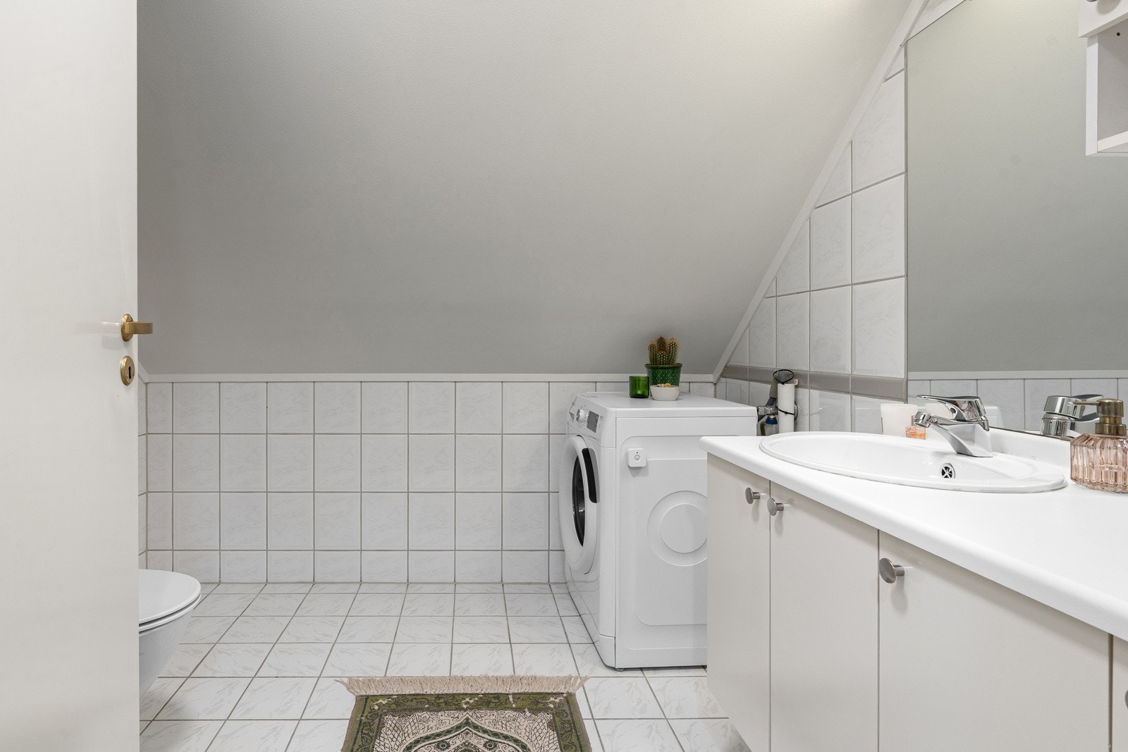 Romslig flislagt bad med plassbesparende løsninger og varmekabler i gulv.