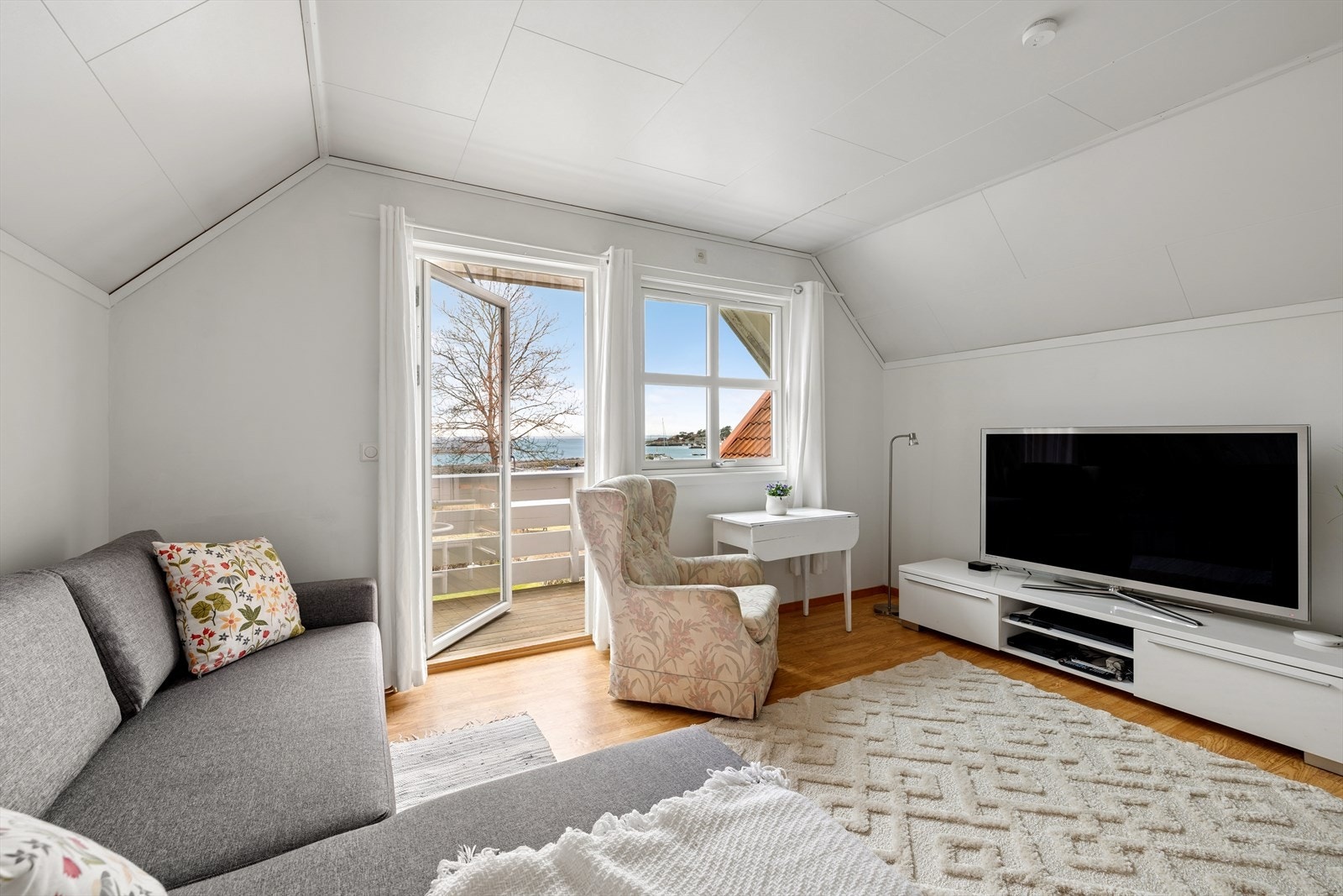 En lys og fin loftstue med plass til sofakrok og TV-møblement. De store høydepunktet er utgang til balkongen. Galleribilde