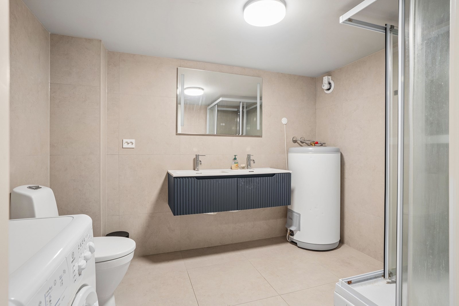 Badet i kjelleren har dusjkabinett, toalett og nedfelt servant med innredning. Det er opplegg for vaskemaskin. Galleribilde