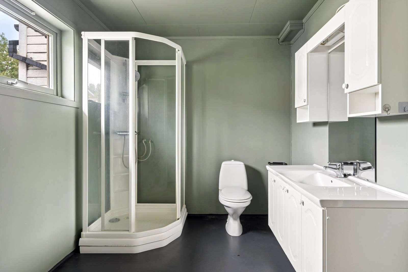 Badet i 1. etasje fungerer også som vaskerom og har innredning med nedfelt servant, toalett og dusjkabinett. Galleribilde
