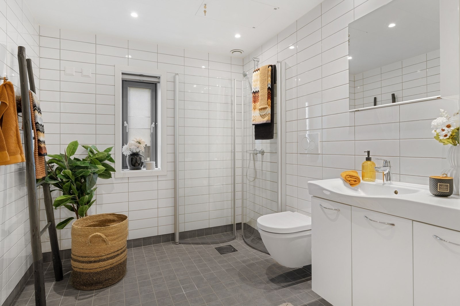 Badet har flislagte overflater, gulvvarme og downlights i himling. Øvrig innredning består av dusjnisje, toalett, opplegg for vaskemaskin og en lys baderomsinnredning med god lagringsplass. Galleribilde