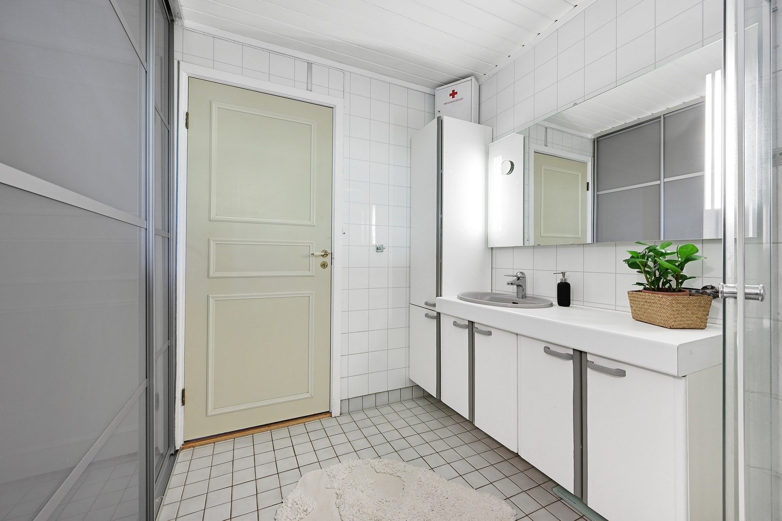 Her finner du vegghengt toalett (2014), dusjhjørne med glassvegger, nedfelt servant i moderne innredning samt opplegg for vaskemaskin skjult bak en smart skyvedør Galleribilde