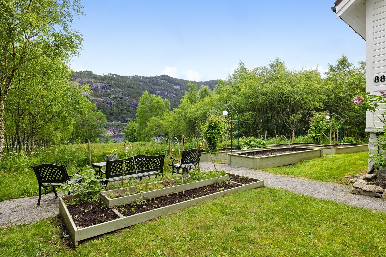 Opparbeidet kjøkkenhage med plantekasser og sitteplass - perfekt for både dyrking og rolige pauser i solen. Galleribilde
