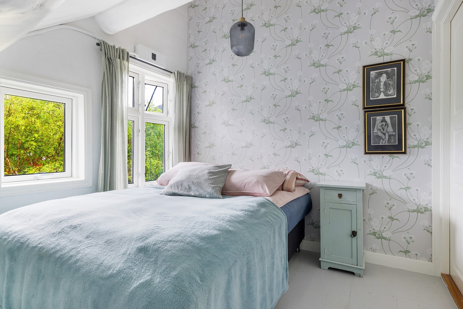 Lyst og sjarmerende rom med blomstrete tapet og myke fargetoner som skaper en rolig og lun atmosfære. Galleribilde