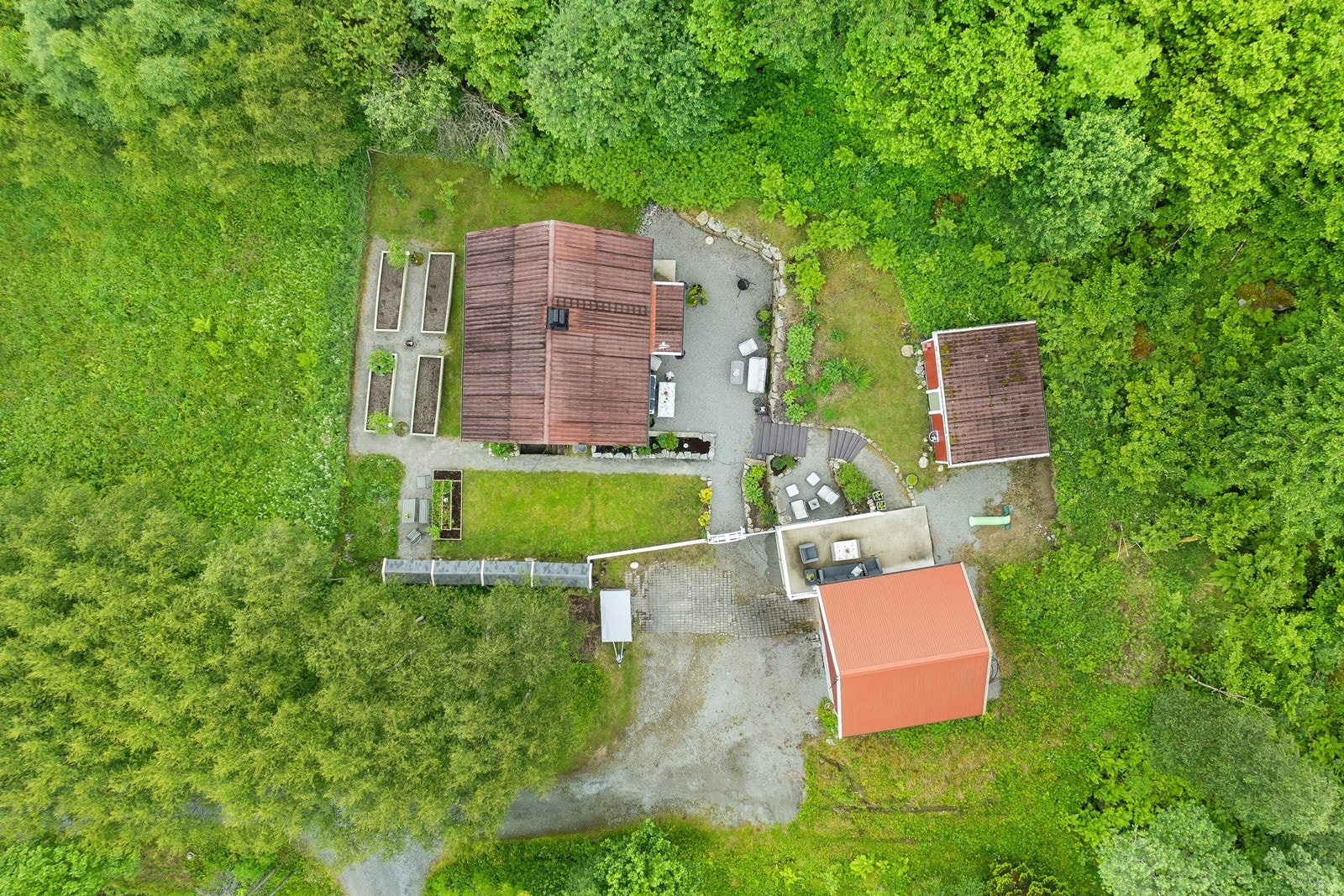 Oversiktsbilde som viser eiendommens fine plassering i terrenget, omgitt av frodig natur. Galleribilde