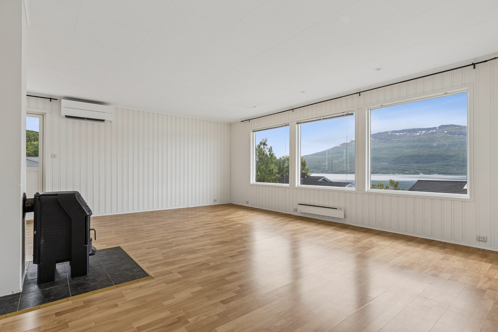 Store vindusflater rammer inn utsikten over fjorden og fjellene. Galleribilde