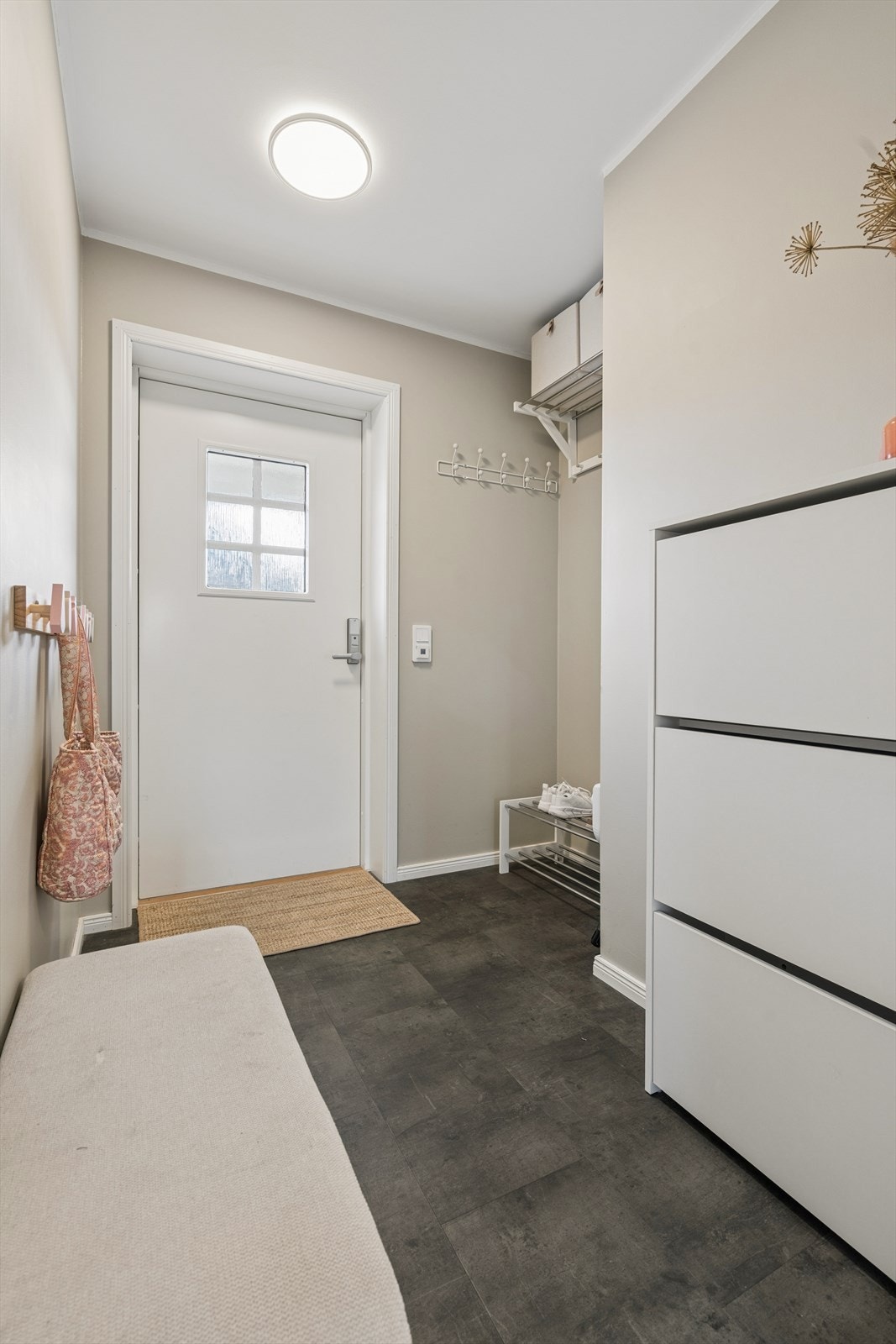 Entréen har mørkt vinylbelegg med termostatstyrt varme på gulvet, som danner en fin kontrast til parketten videre inn i boligen. Her er det god plass til yttertøy og sko, med mulighet for både skohylle og oppbevaring langs veggen. Galleribilde