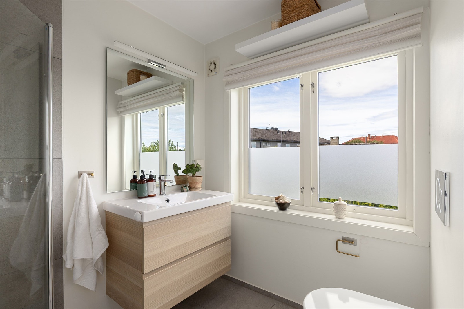 Lekkert "en suite" bad som ble oppusset i 2017. Dusjhjørne med innfellbare dusjvegger i glass. Grå fliser på vegg og mosaikkfliser på gulv i dusjsone. Vegghengt toalett og servantskap med speil og overlys. Galleribilde