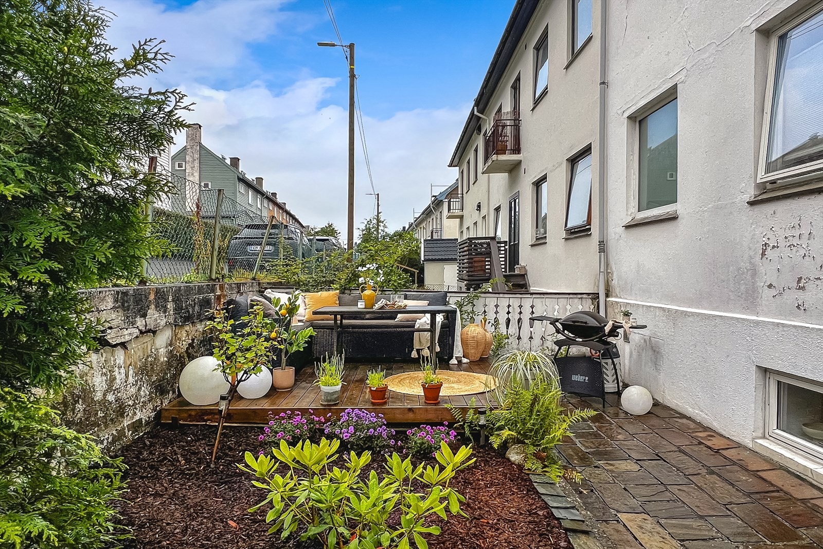Leilighetens uteplass er pent opparbeidet med terrasseplatting, bed og beplantning. Galleribilde