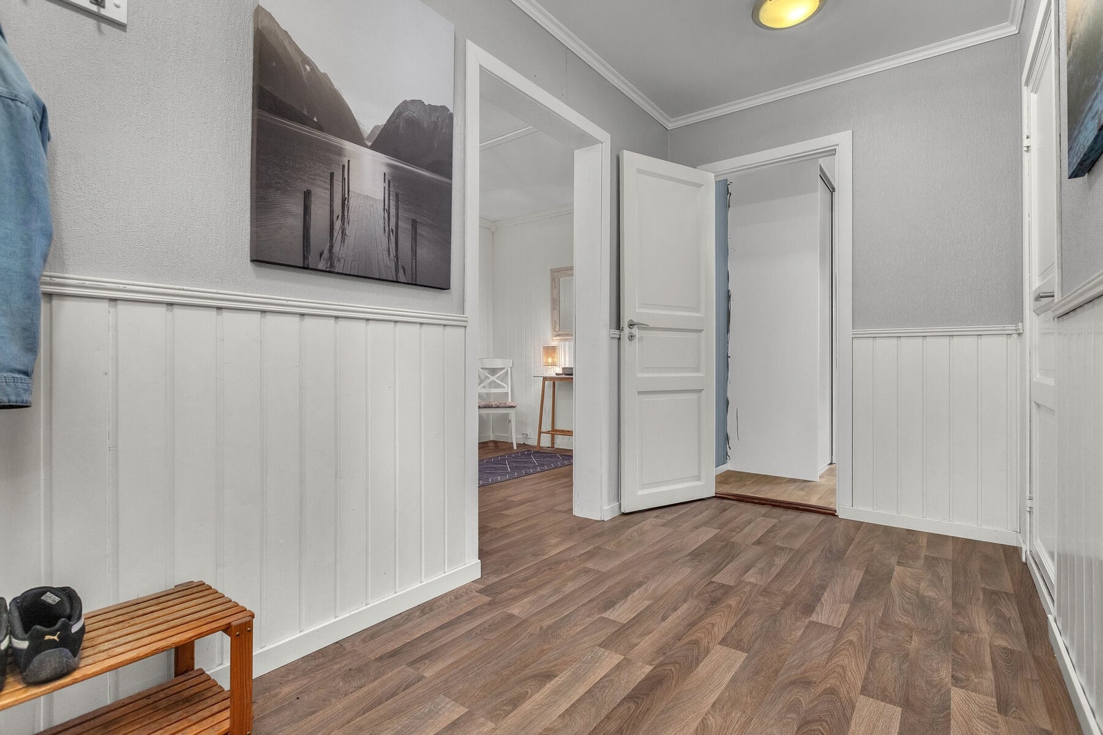 Gangen har vegger med trepanel og laminat på gulvet, som er gjennomgående i store deler av boligen. Galleribilde