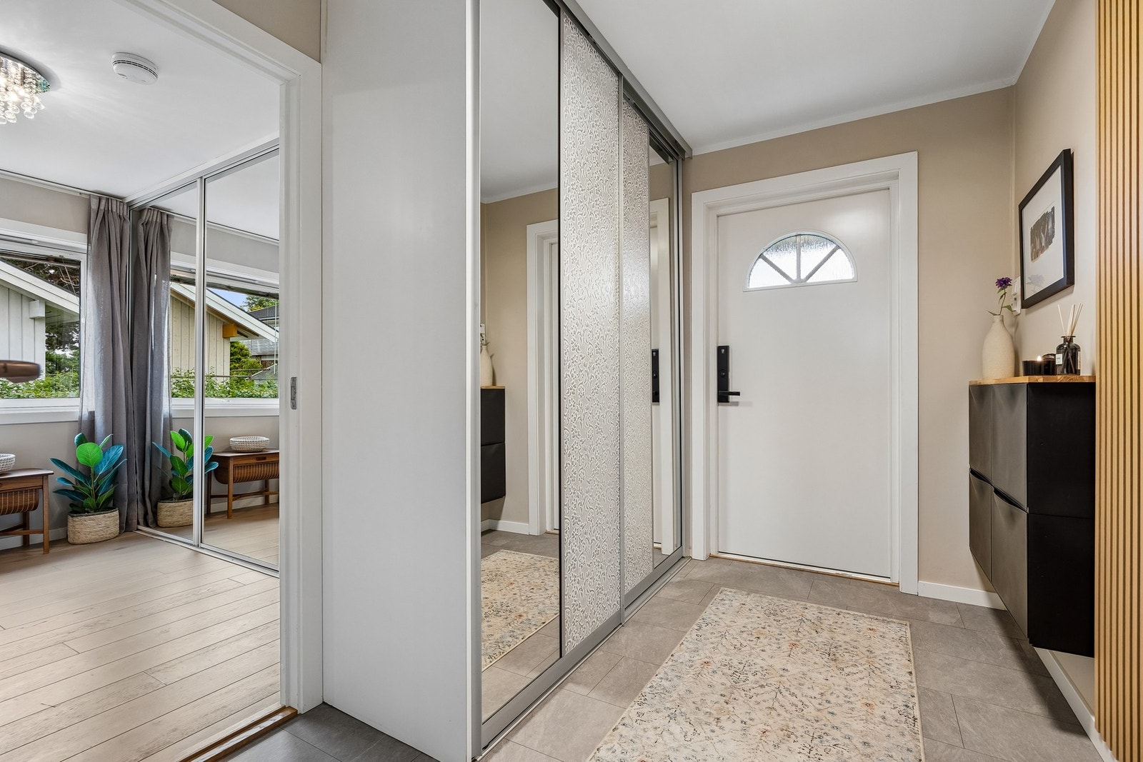 Entréen fremstår innbydende med slitesterkt laminatgulv, varmekabler og en praktisk skyvedørsgarderobe med speilfronter som gir god oppbevaringsplass. Galleribilde